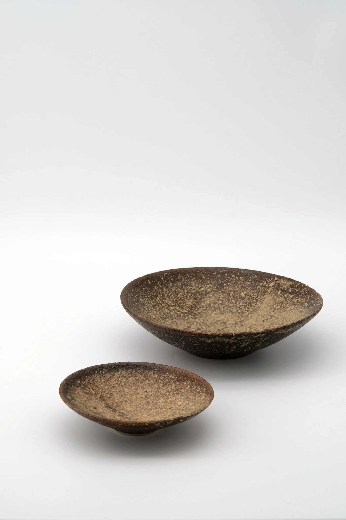 Three brown ceramic bowls with a speckled pattern, arranged against a white background.
