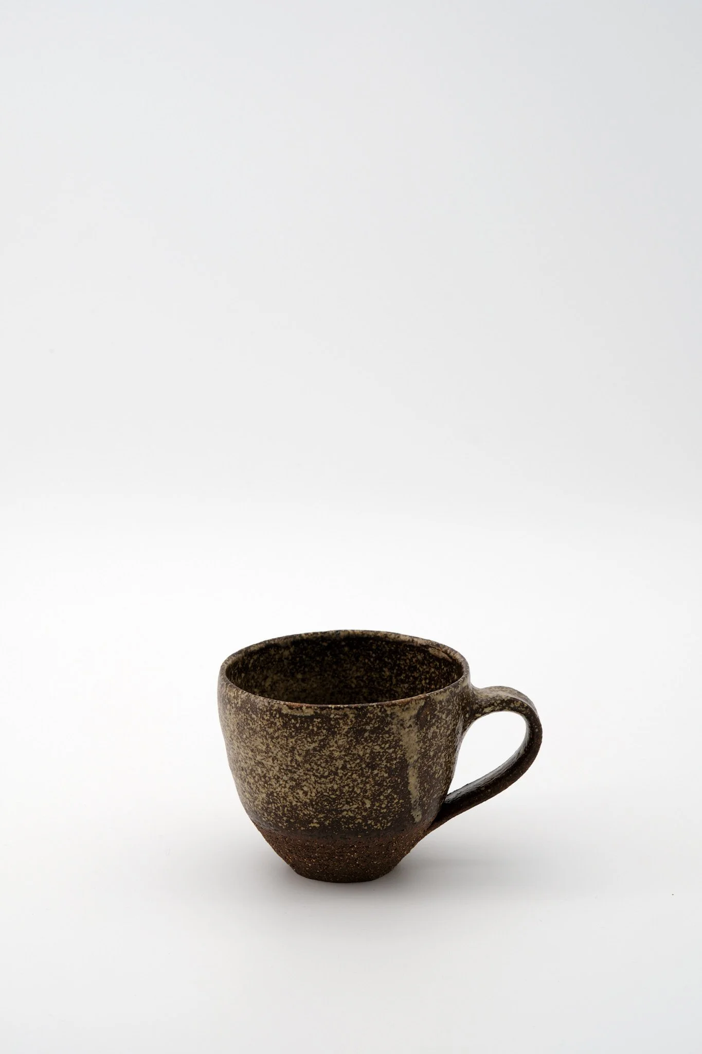A ceramic mug with a speckled brown glaze, placed against a plain white background.