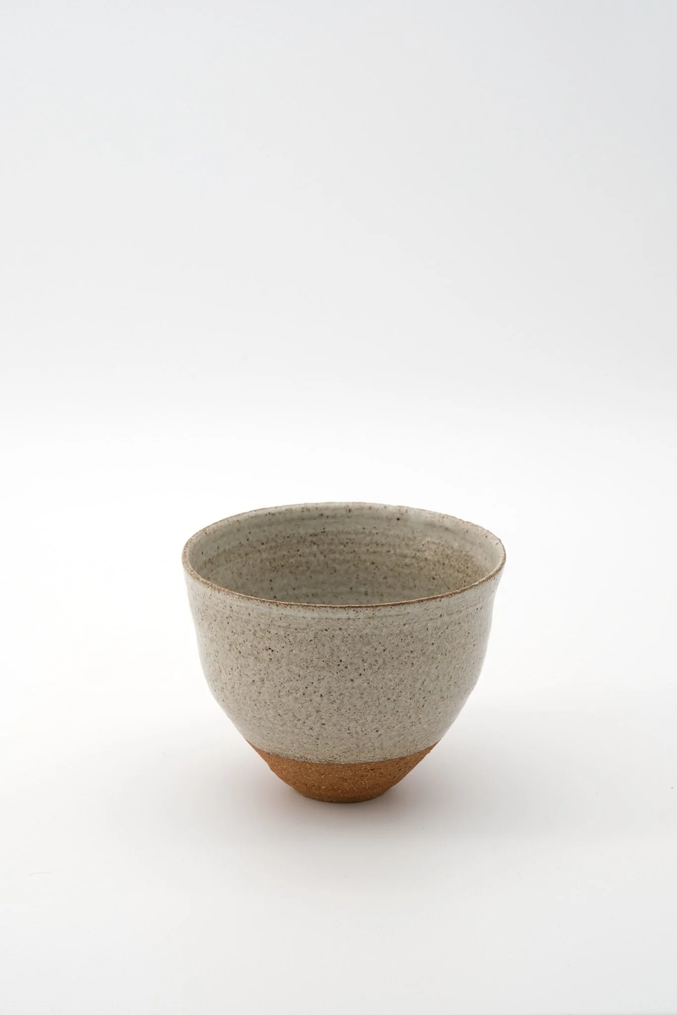A ceramic cup with a speckled white upper section and a brown bottom section, set against a plain white background.