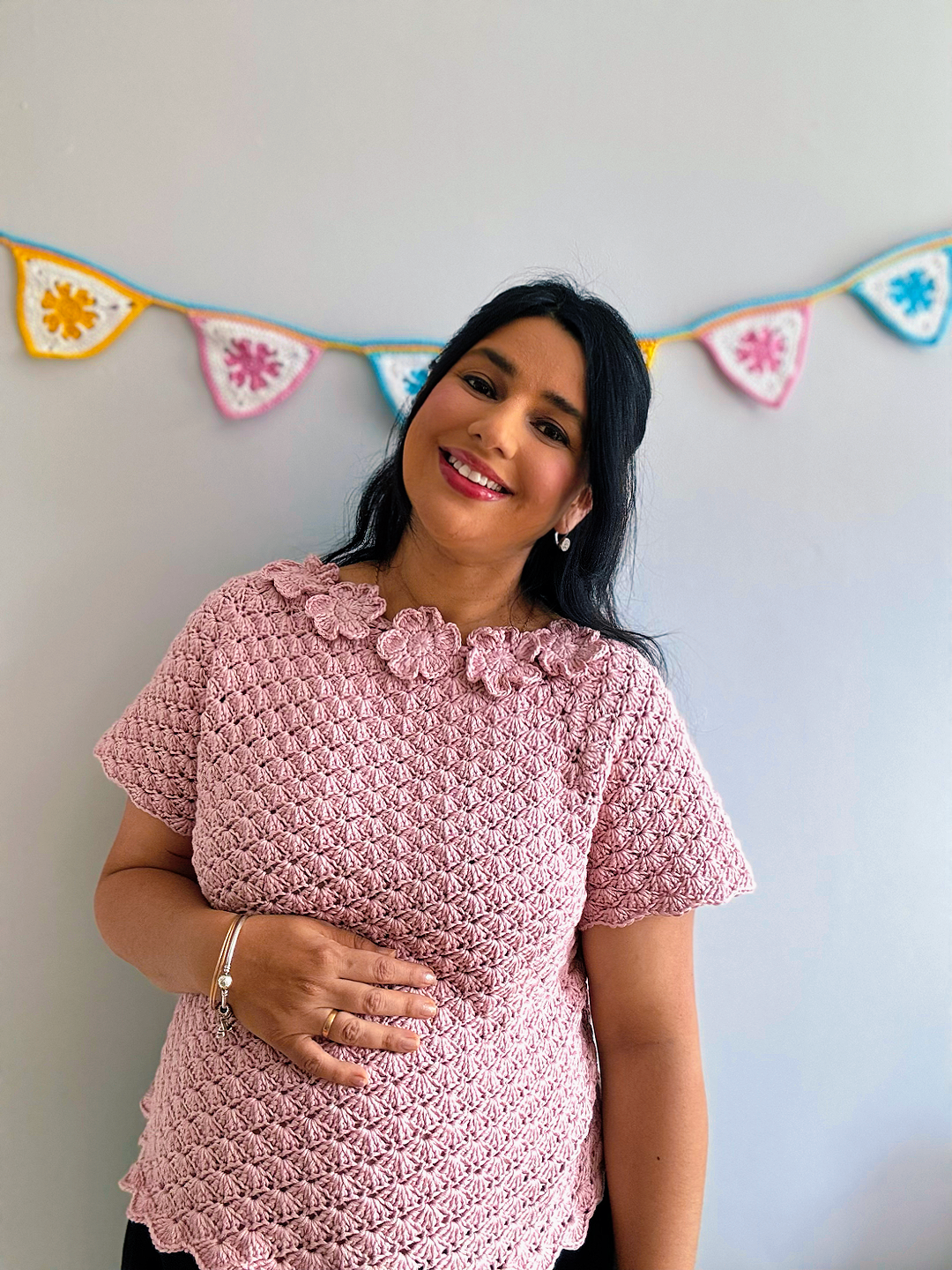 a pregnant woman wearing a crochet top in pink