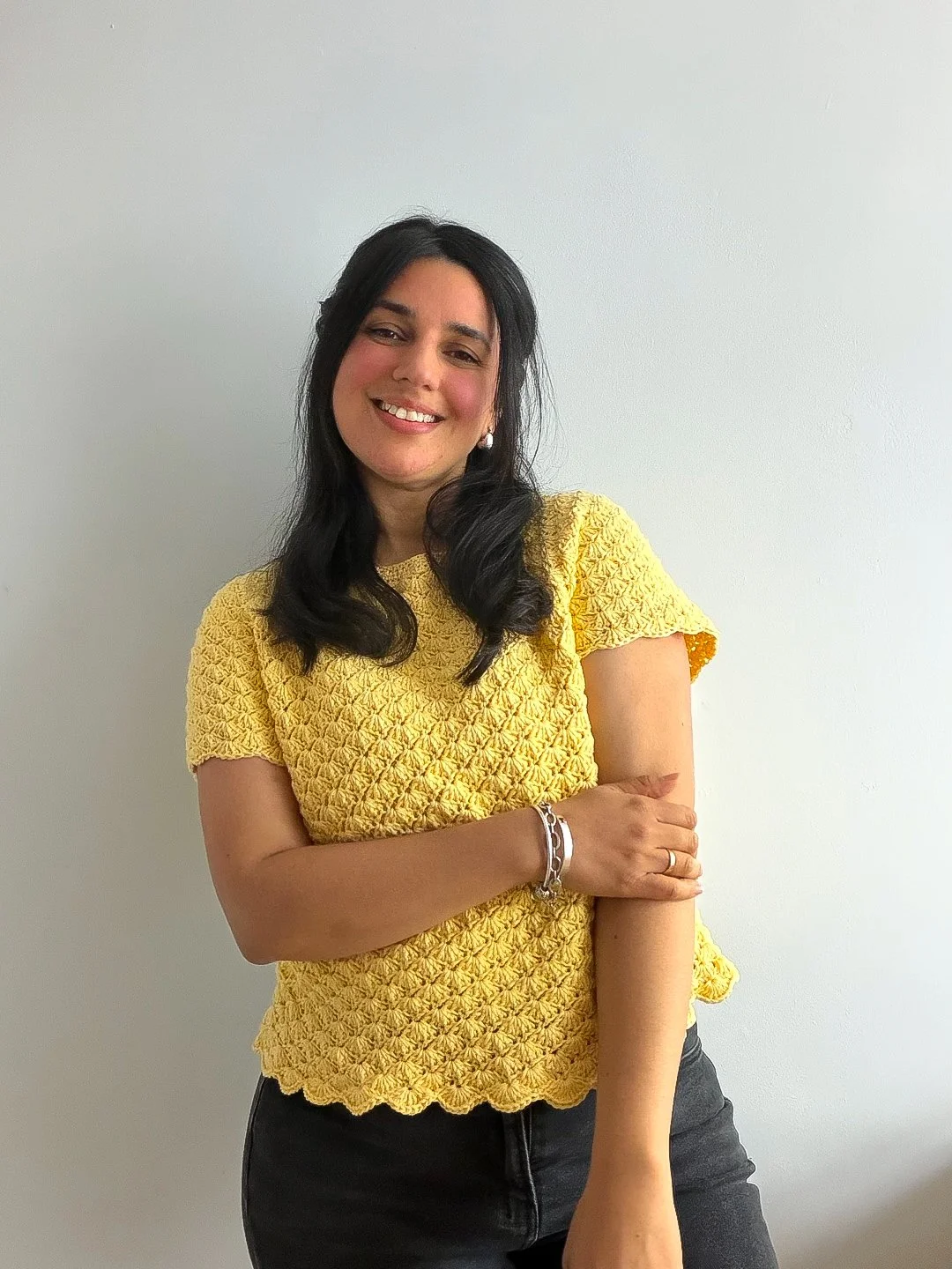 A woman wearing a yellow shell-stitch crochet summer top.