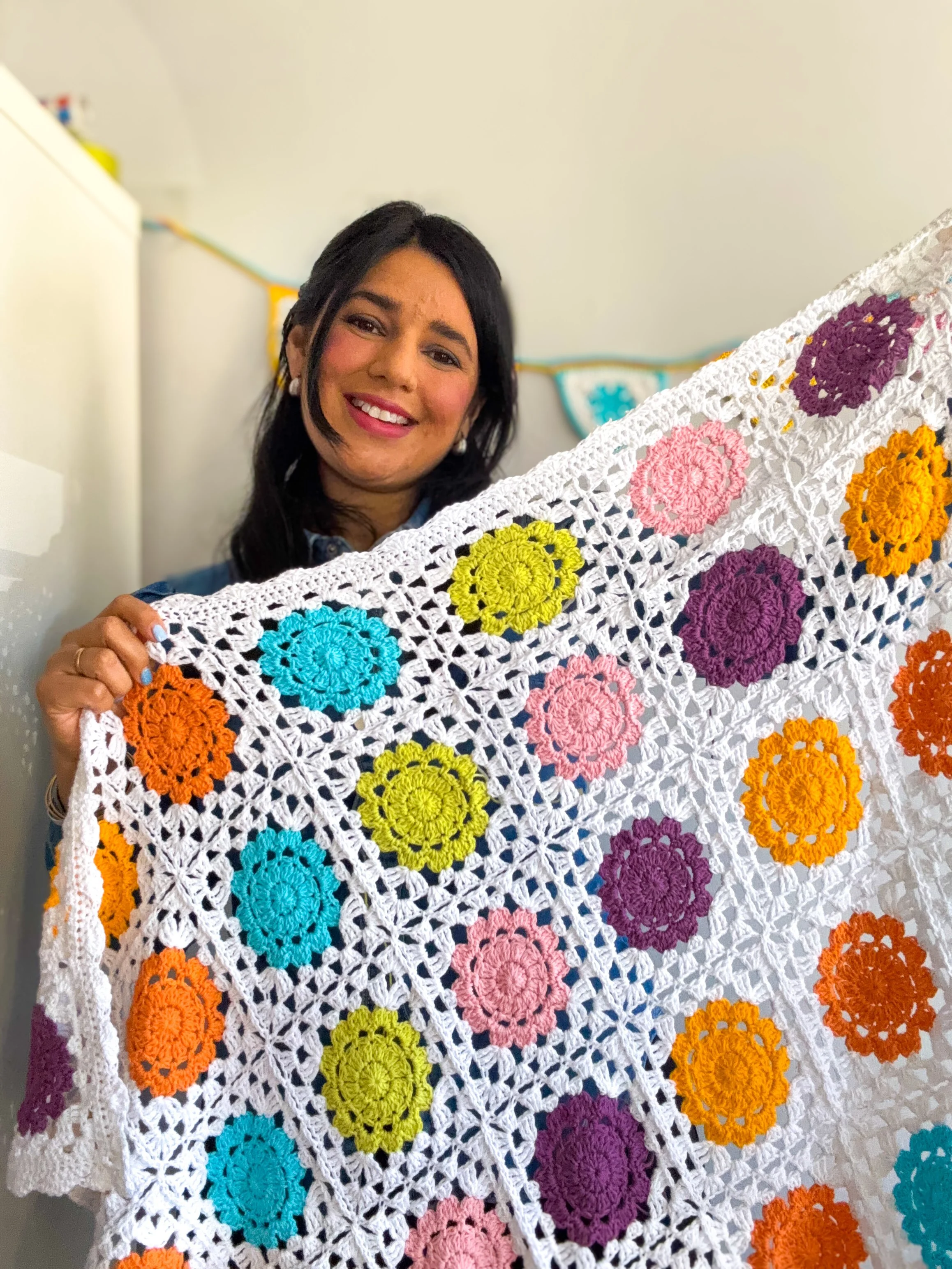 a young woman holding a colorful granny square blanket