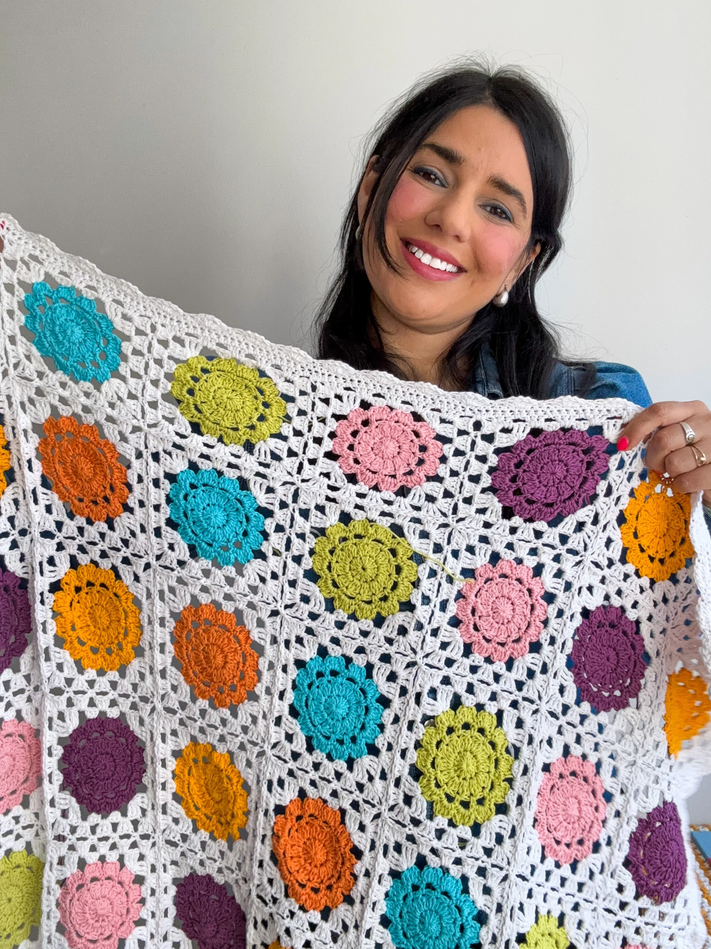 a young woman holding a crochet granny square
