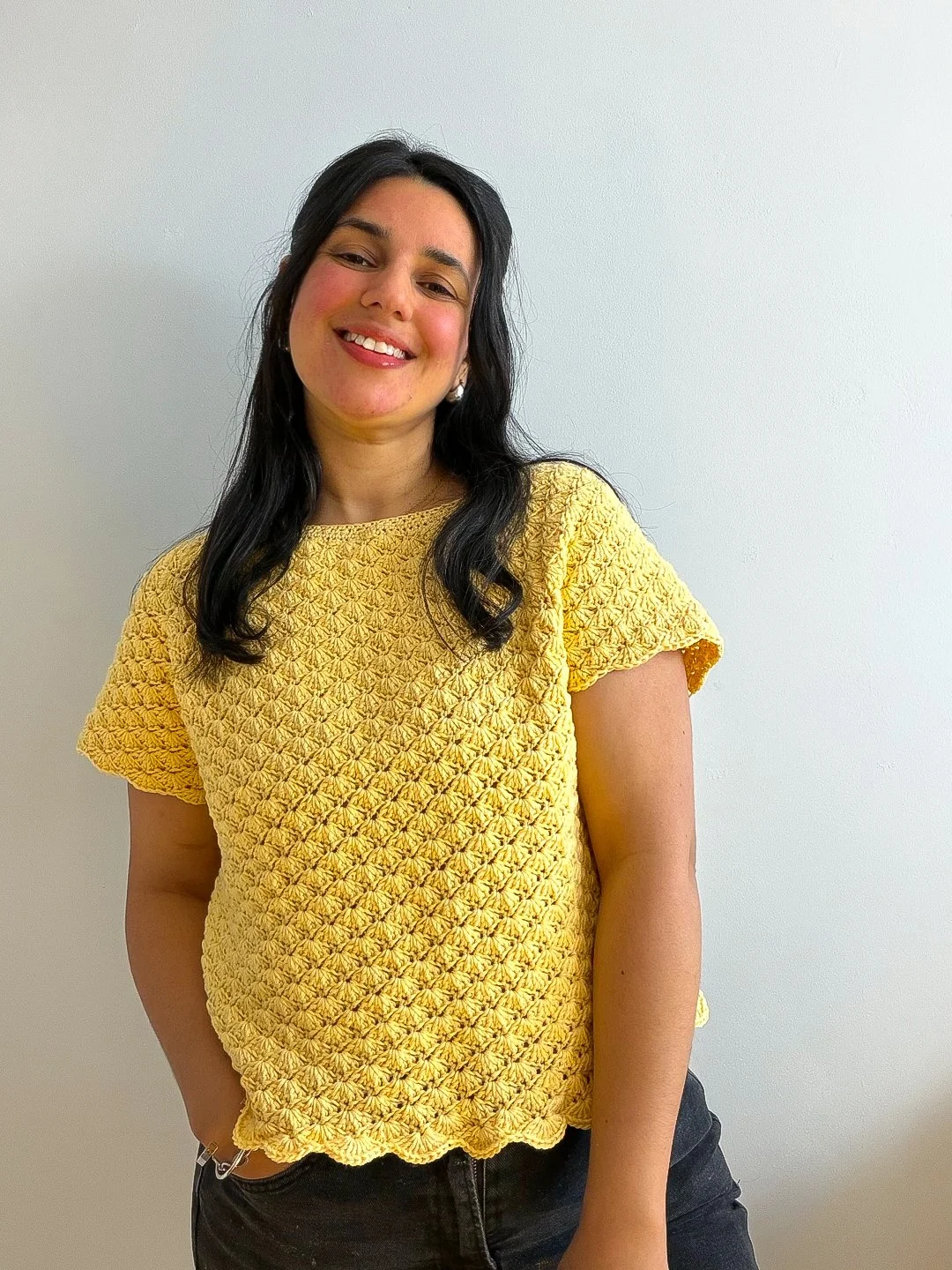 a woman wearing a crochet shell stitch summer top in trending summer color yellow