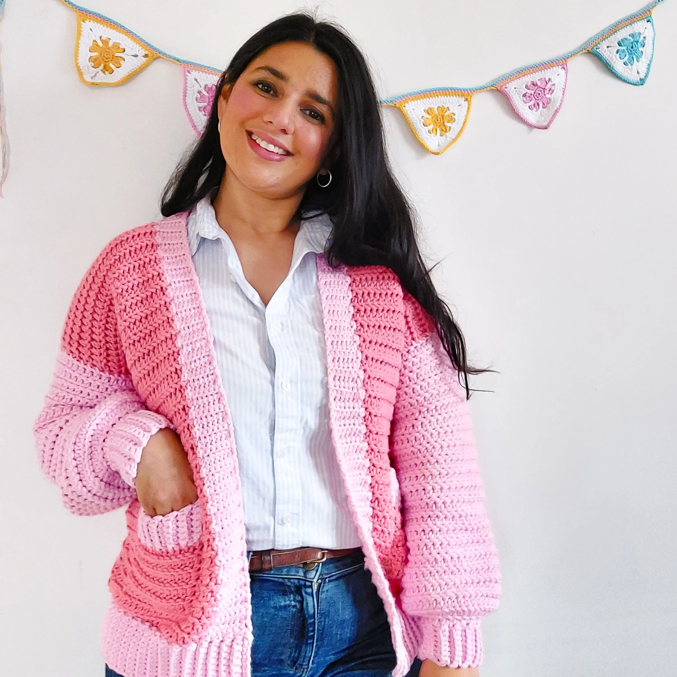 woman in her thirties wearing a crochet pink cardigan with pockets