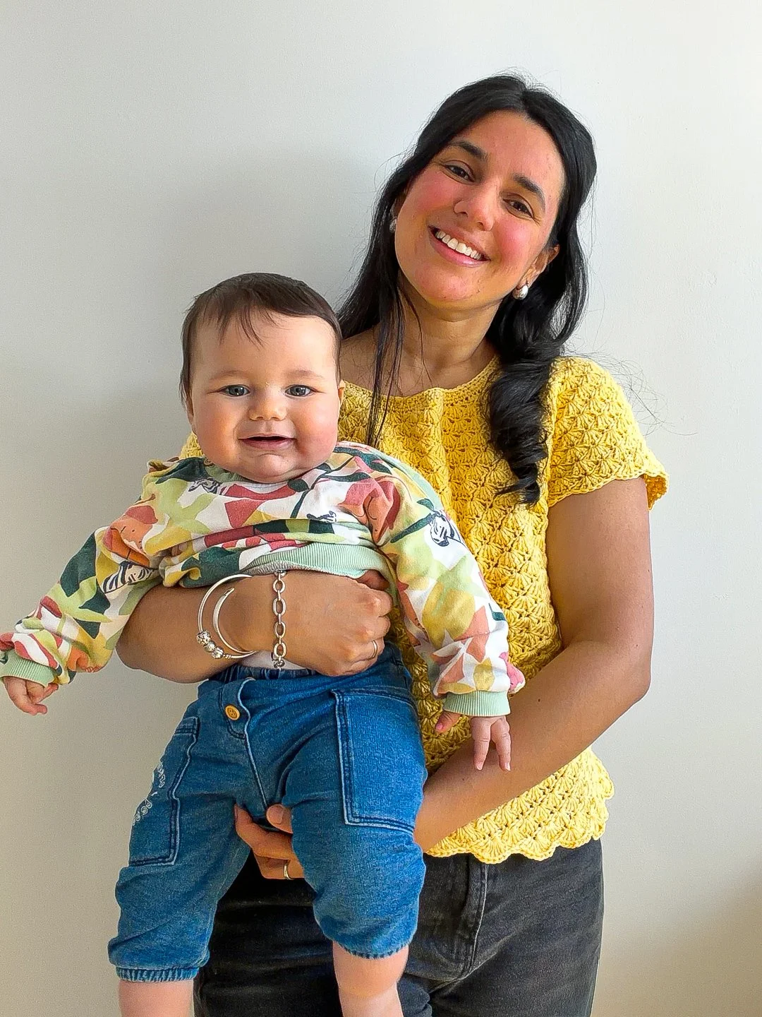 a woman holding her baby and wearing a shell stitch crochet summer top