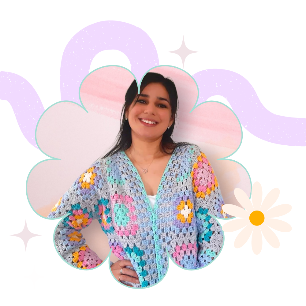 Smiling person wearing a colorful crochet cardigan with floral and star graphics.