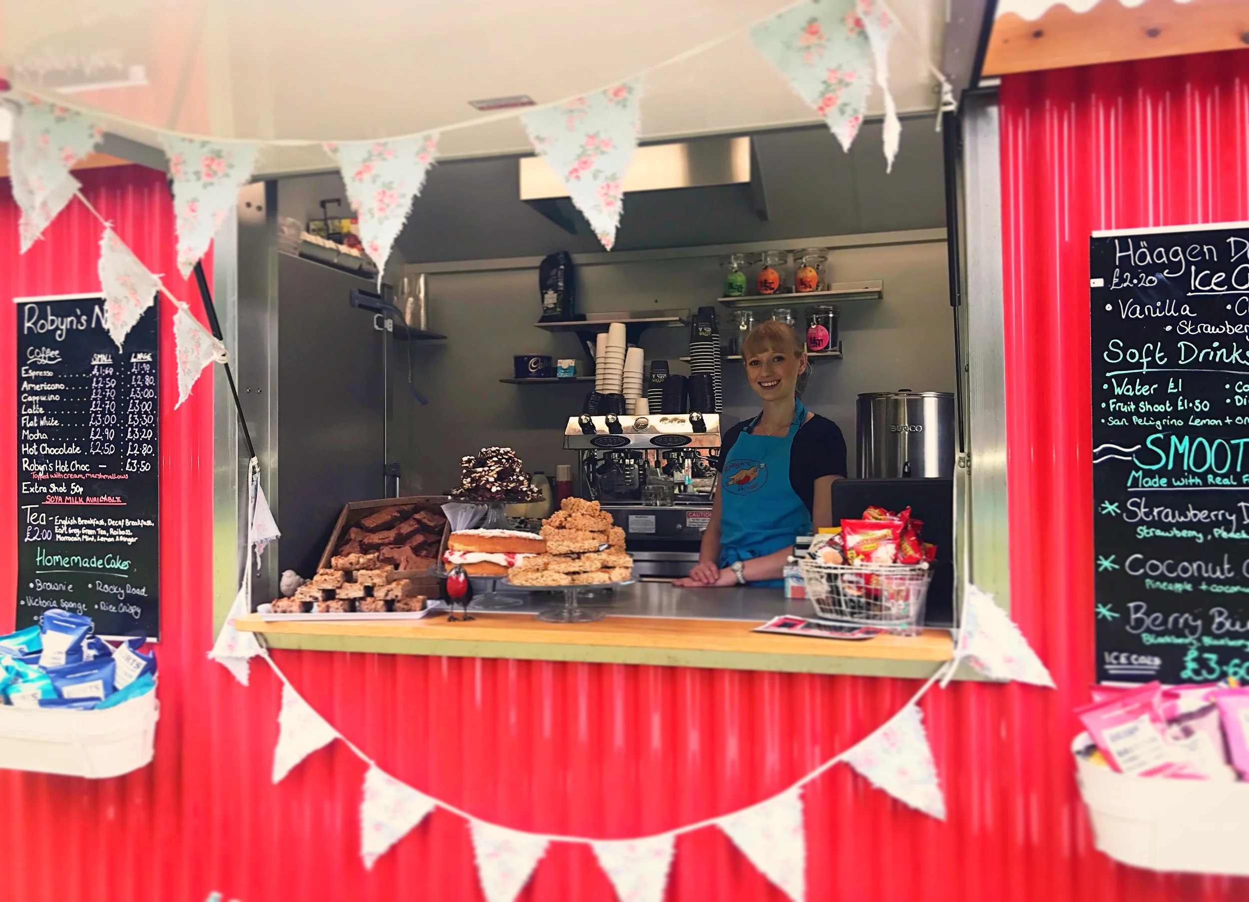 Robyn in the red shepherds hut when she started the business in 2016. Cake display on the counter, chalk boards displaying prices
