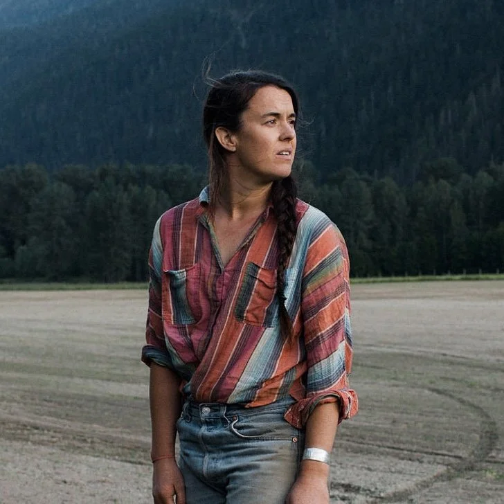 A woman wearing a striped red top and jeans standing in a field