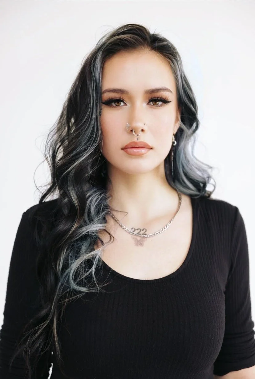 A woman with long dark hair wearing a dark blouse at Vancouver Indigenous Fashion Week.