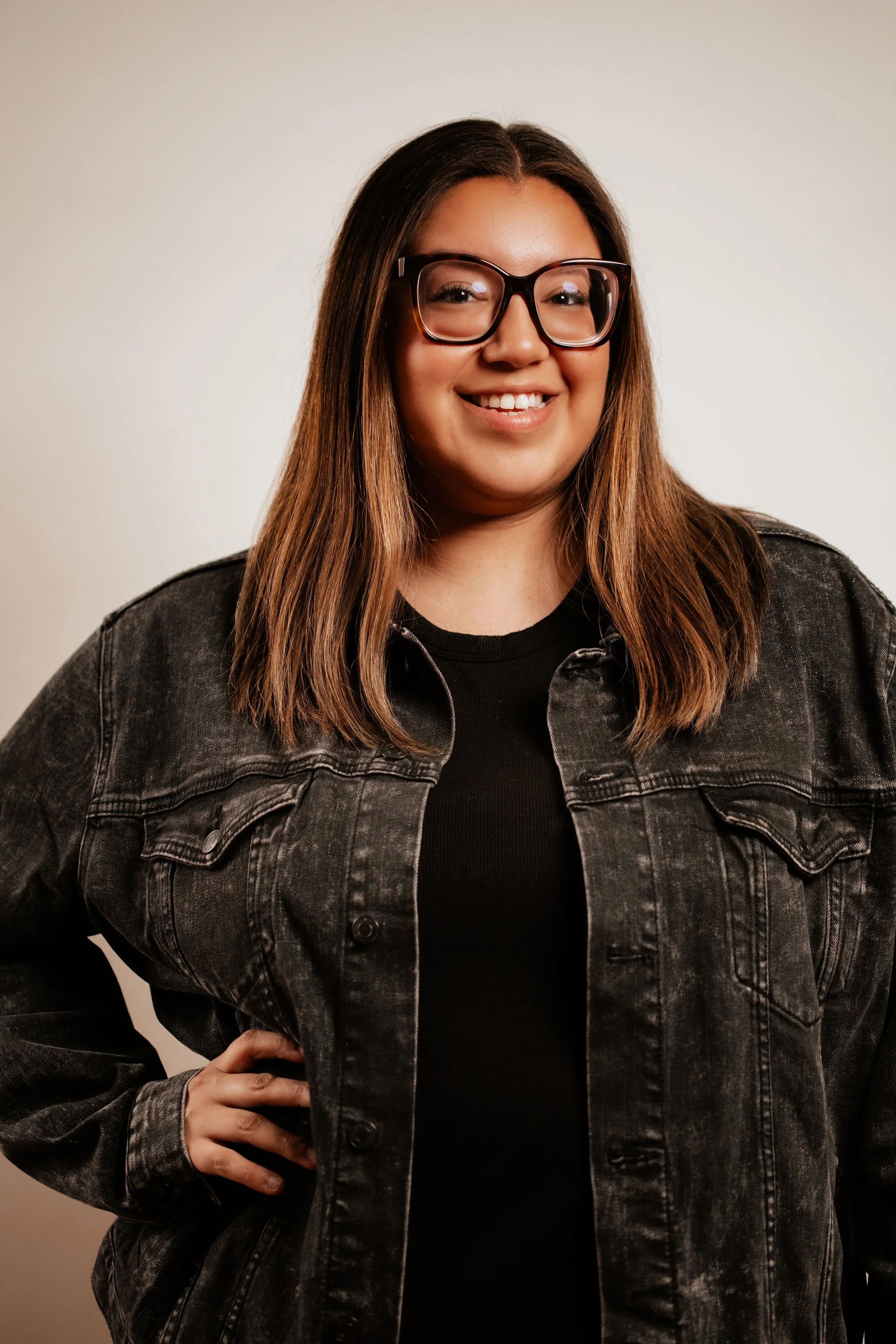 Woman wearing glasses and a jean jacket, smiling at Vancouver Indigenous Fashion Week.