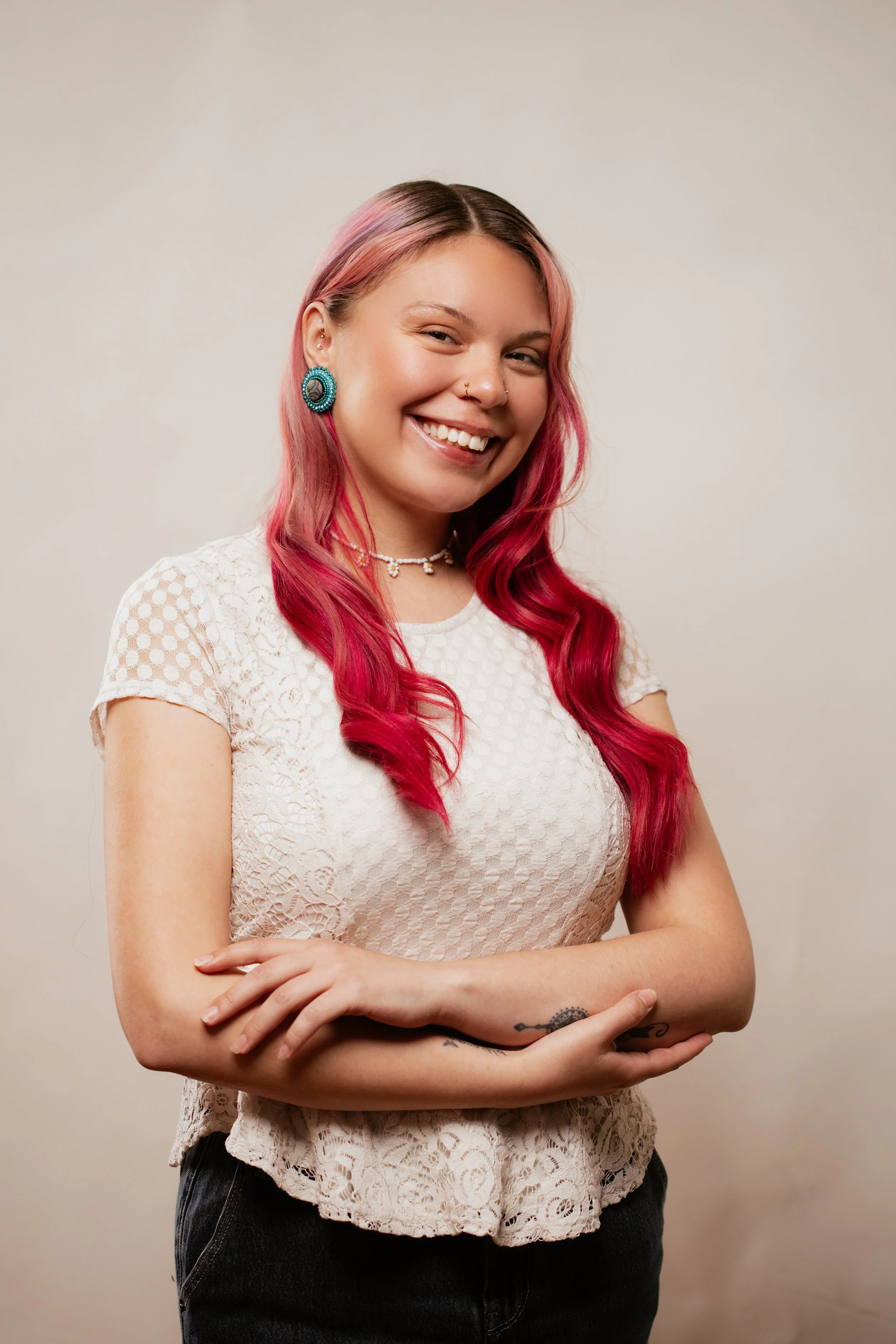 A woman with long red and pink hair in a white blouse smiling at Vancouver Indigenous Fashion Week.