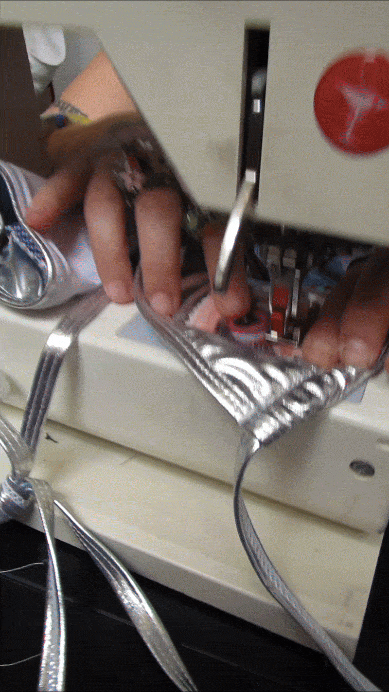Close-up of hands wiring electrical connections on a circuit board, with wires and tools visible.