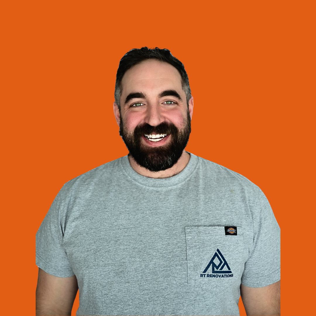 Bob Timm, owner of RT Renovations- smiling, wearing a dark green button-up shirt, indoors with staircase in background.