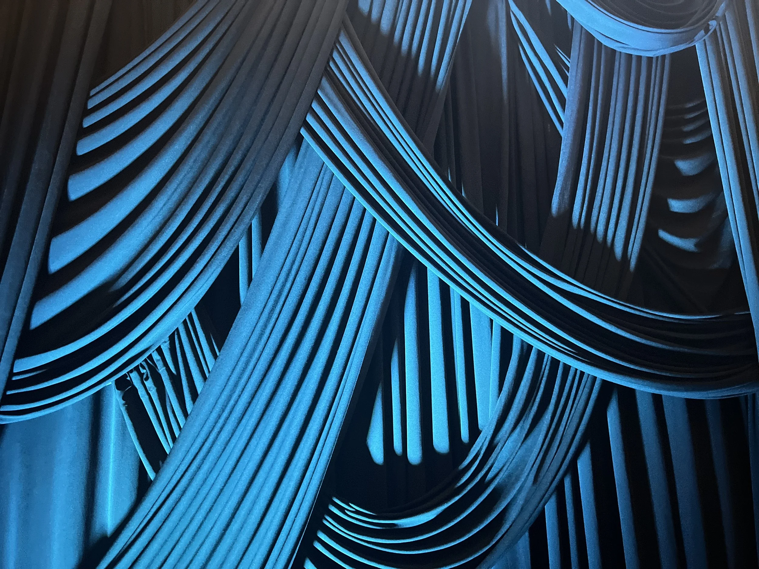 Close-up view of blue stage curtains with dramatic folds and lighting.