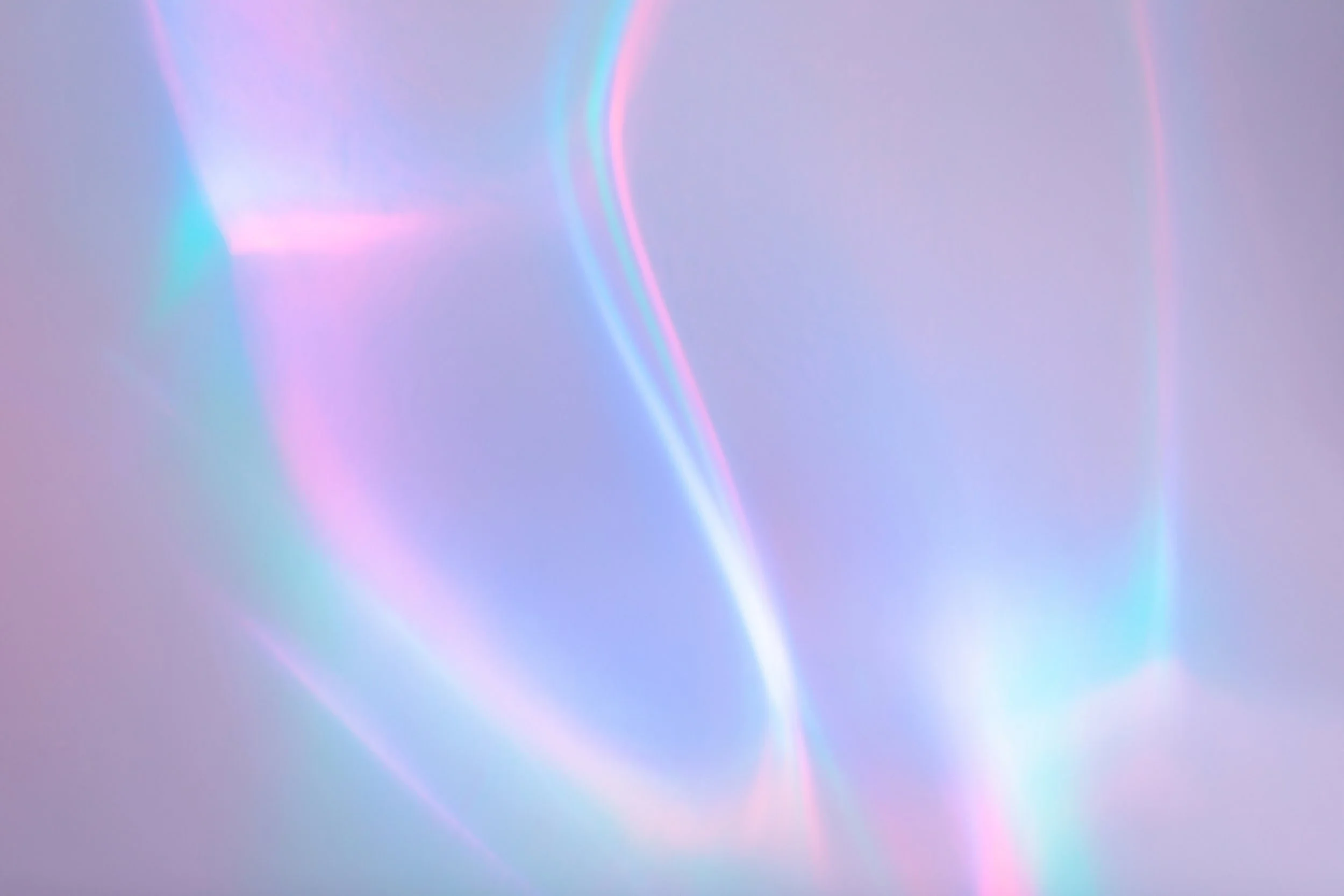 Soft pastel colored iridescent light streaks and reflections on a smooth surface.