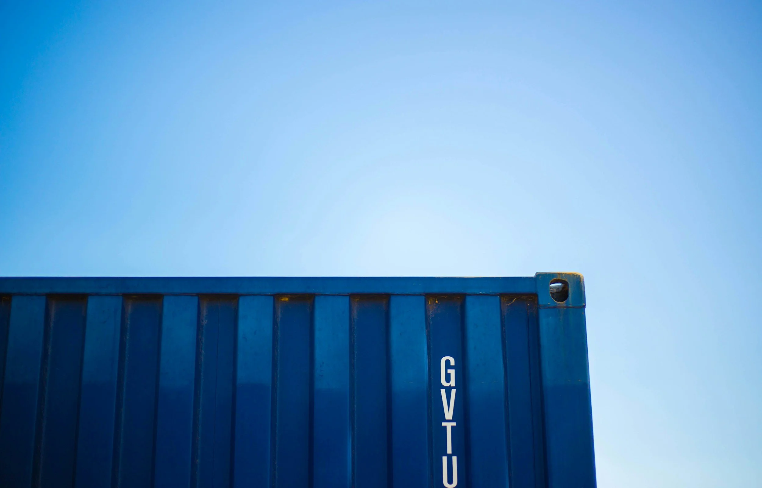 A blue shipping container against a clear blue sky during daytime.
