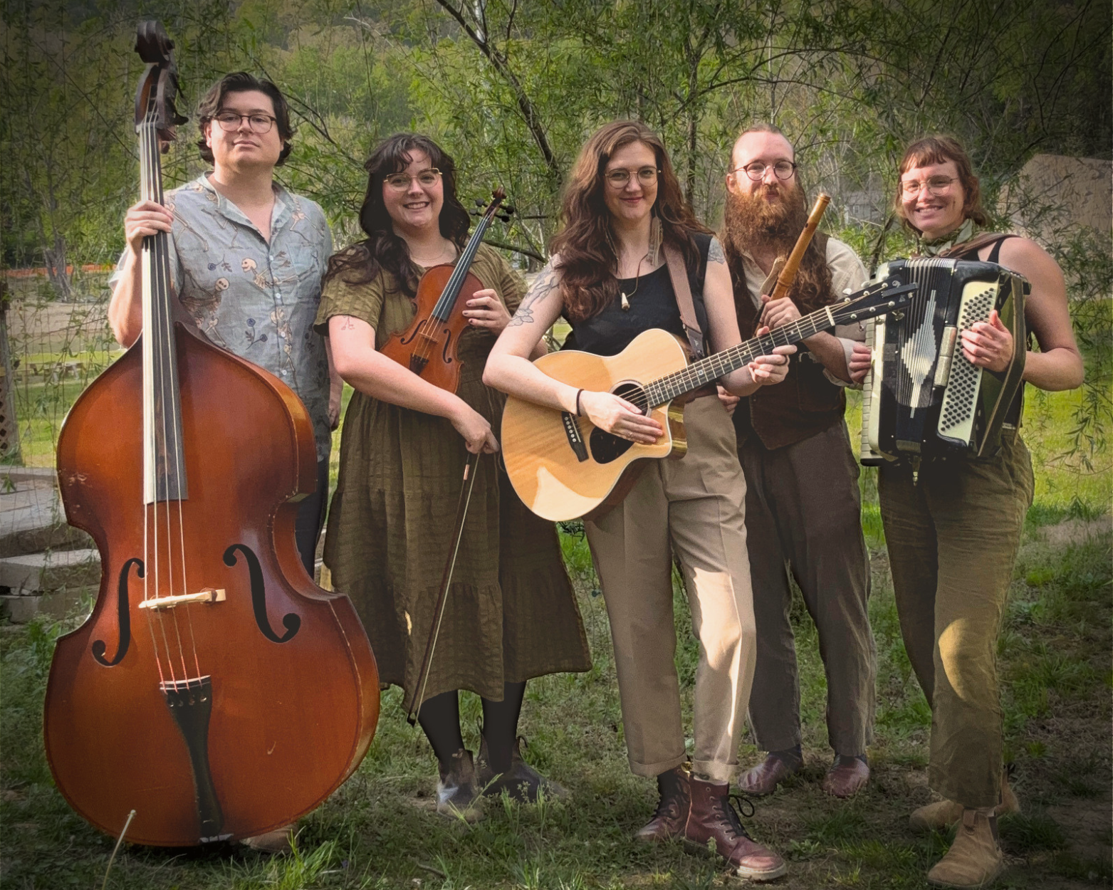 All 5 members of Holler & Crow stand outdoors playing various instruments including bass, violin, guitar, flute, and accordion.