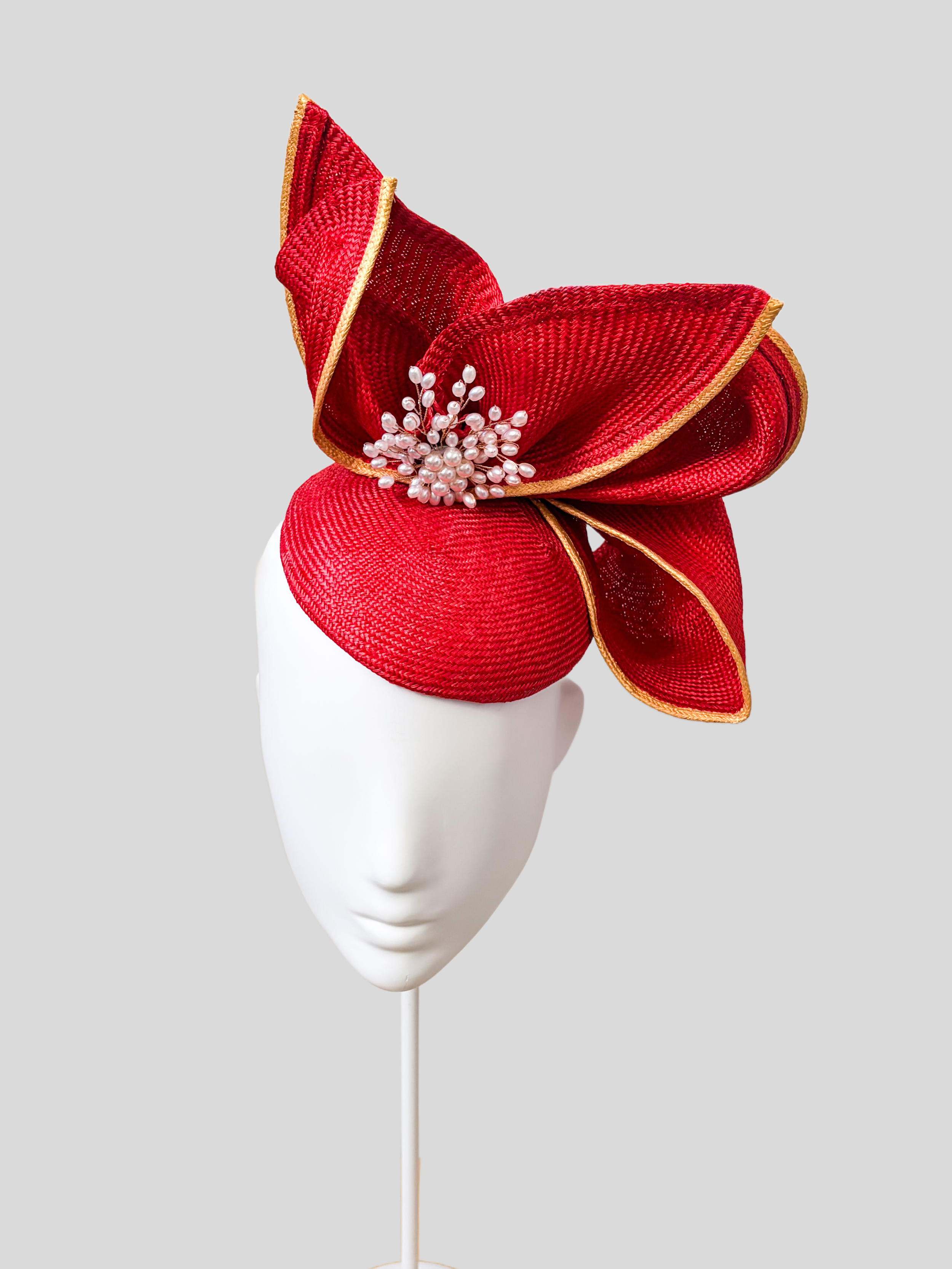 Aria Ruby sculptural Parisisal headpiece in vibrant red with metallic gold edging and pearl embellishment.