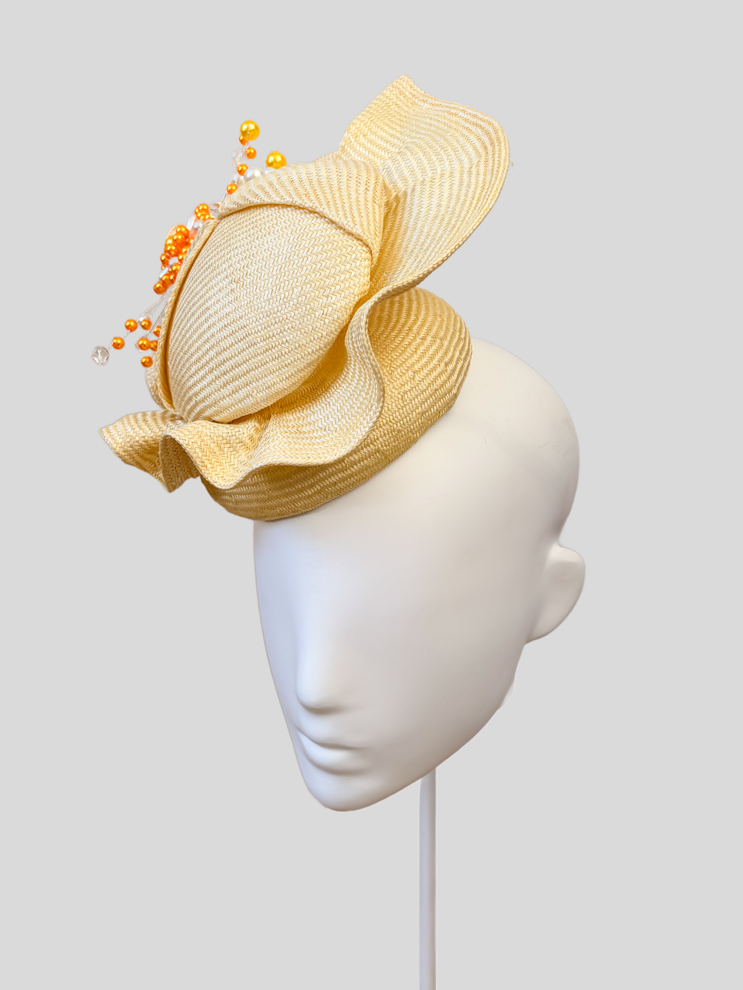 Right: Right-side view of the VÉRA Citrine Parisisal cocktail hat highlighting its luminous light-yellow finish and hand-beaded embellishment.