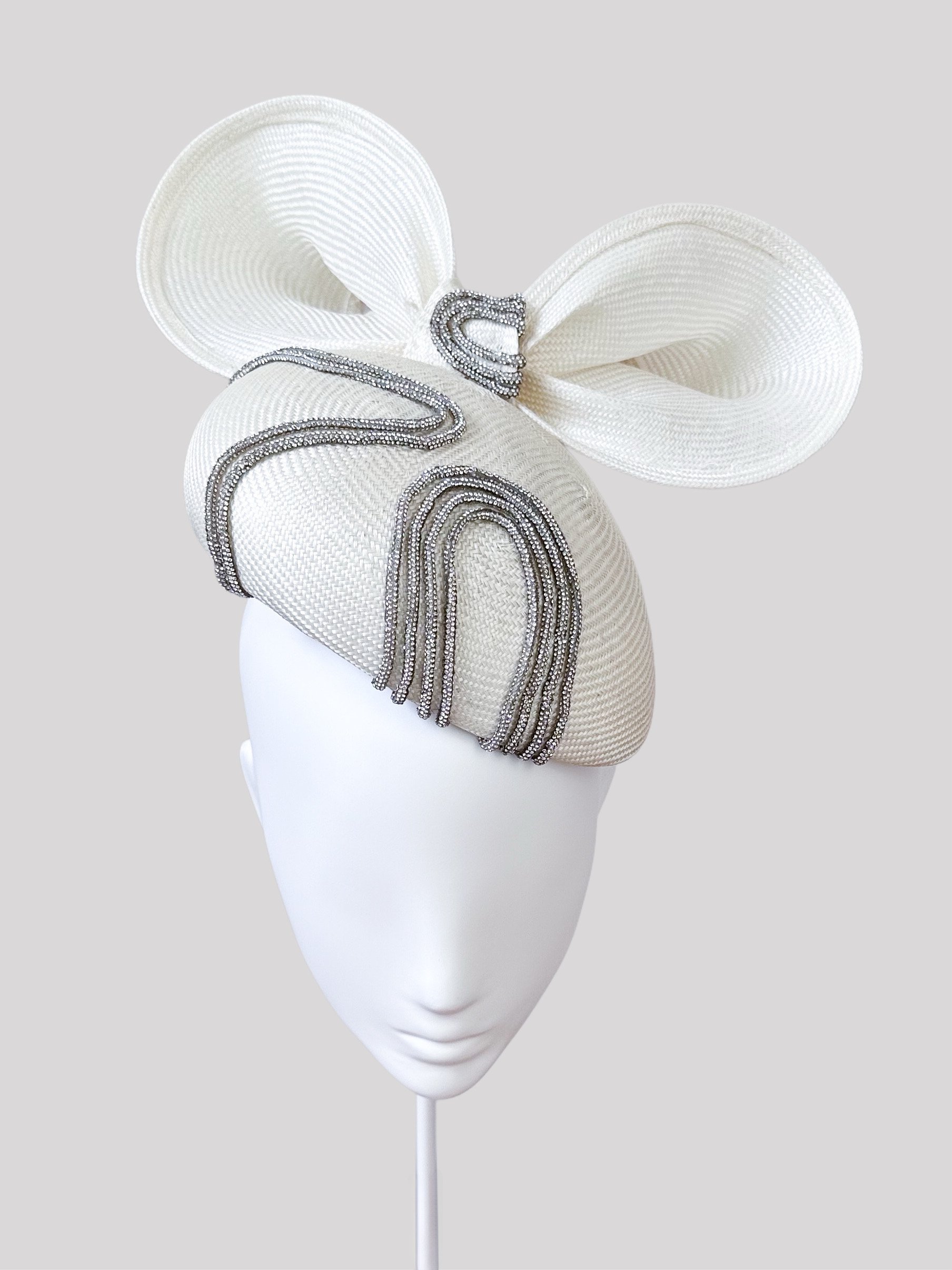 Front view of the "Sfavillio Avorio" ivory face hugger. Showcasing its classic silhouette and the elegant placement of the matching bow and metallic silver rope detail.
