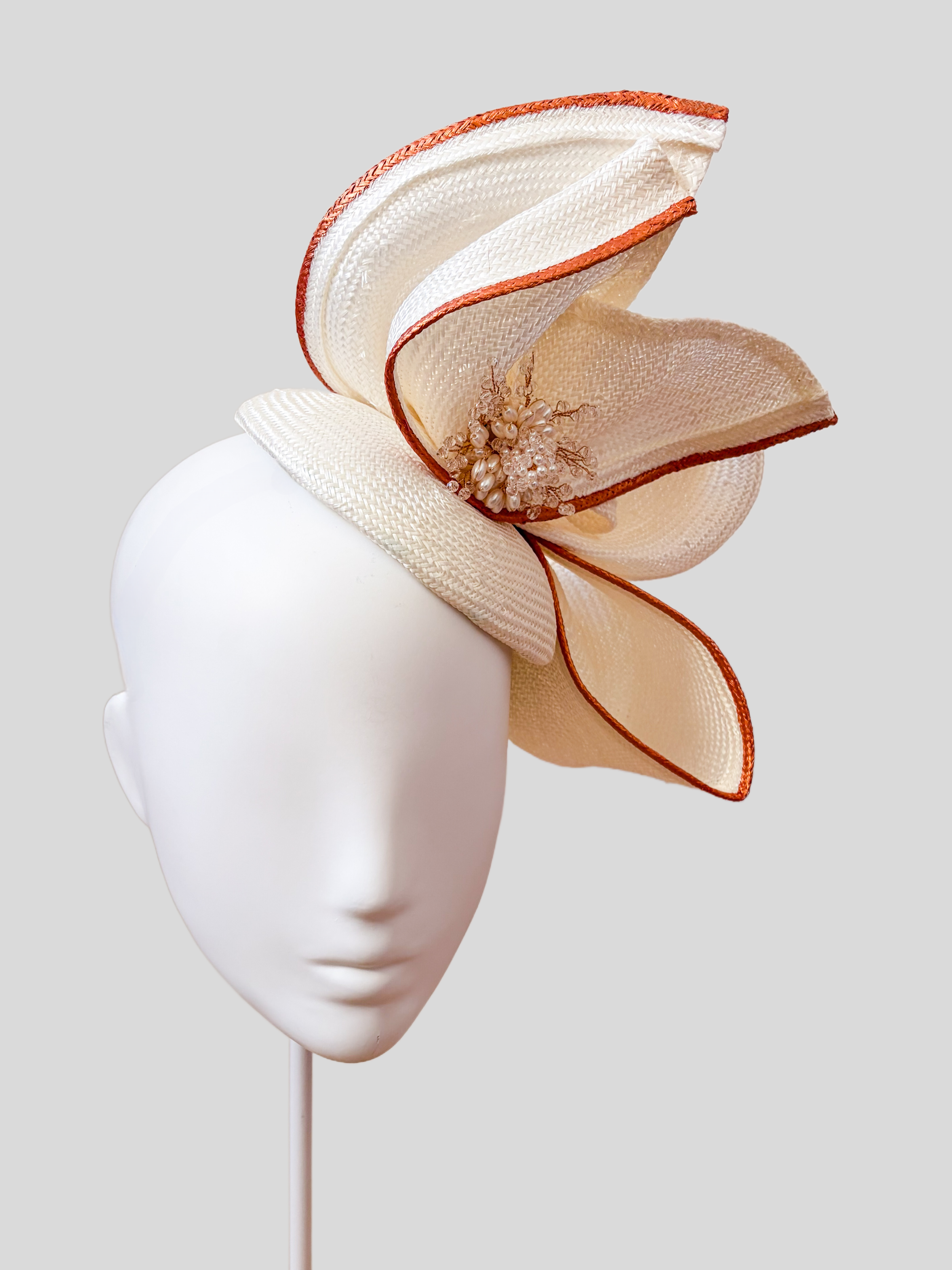 Aria Ivory sculptural Parisisal headpiece in off-white with rose-gold metallic edging and pearl embellishment.