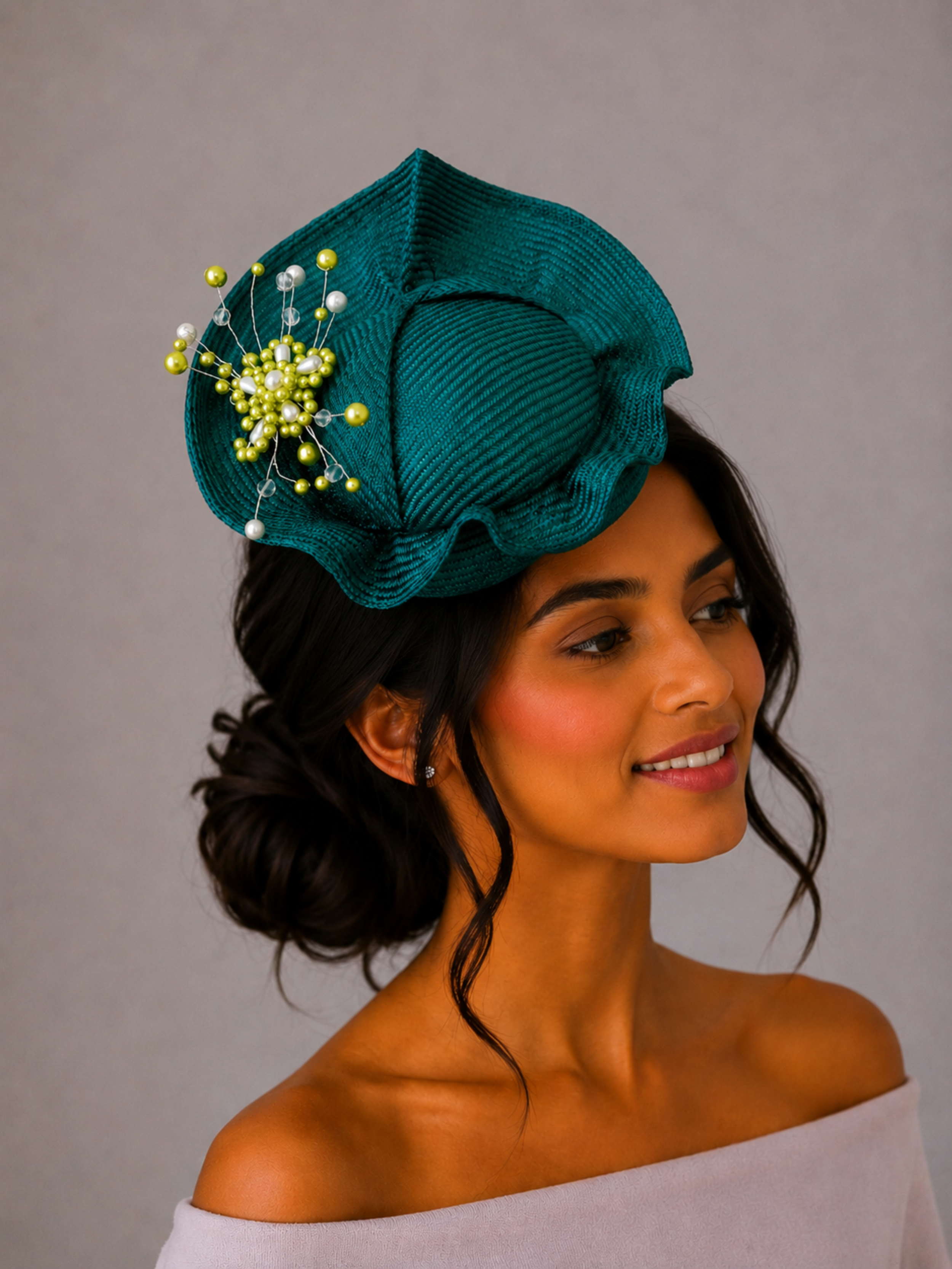 Model: VÉRA Teal Parisisal cocktail hat styled on a model, showcasing its sculptural silhouette and intricate hand-beaded embellishment.