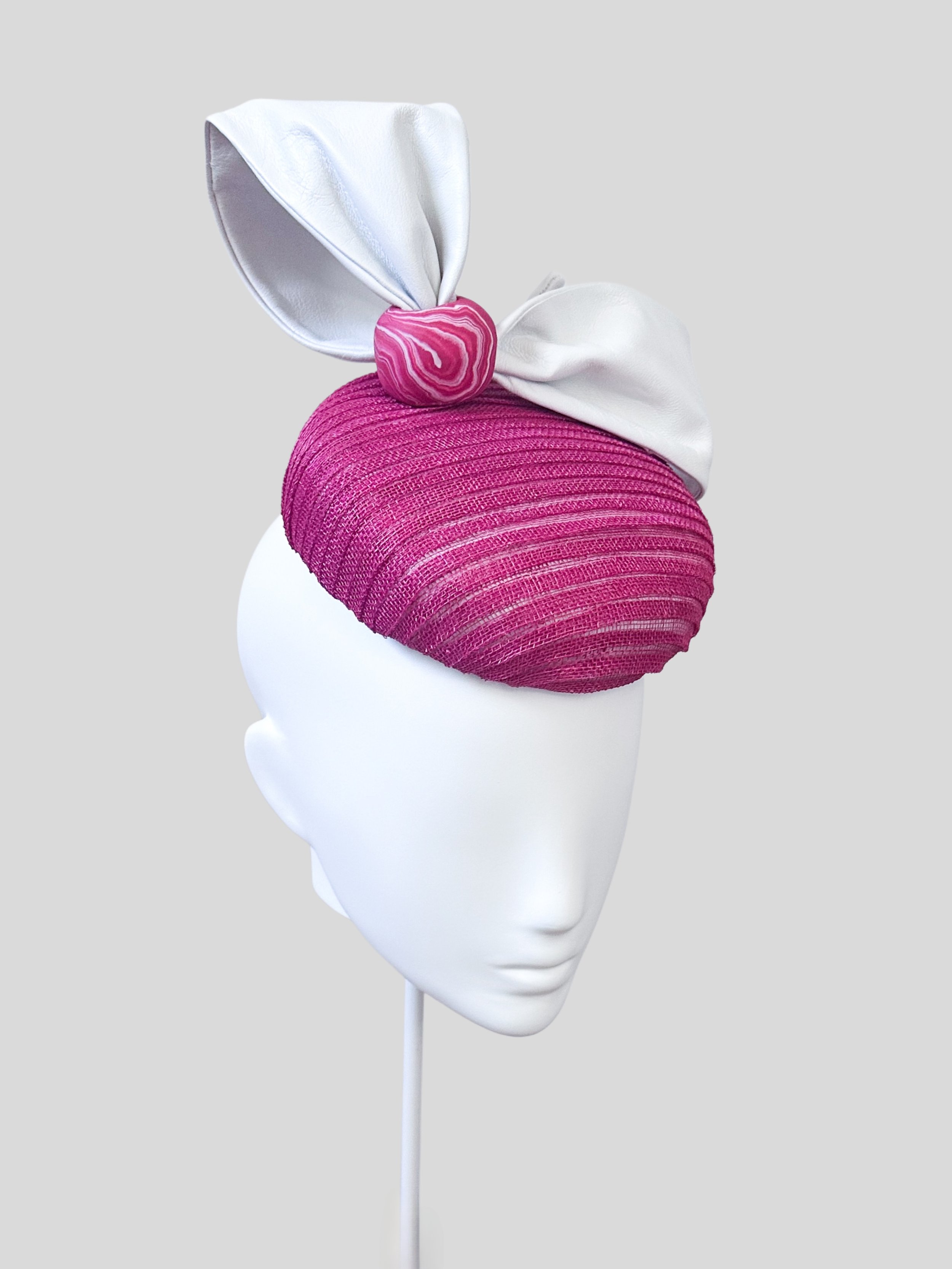 Left side view of the stylish Verano Biancorosa cocktail hat, emphasizing the textured pink base and the elegant white Italian leather trim.