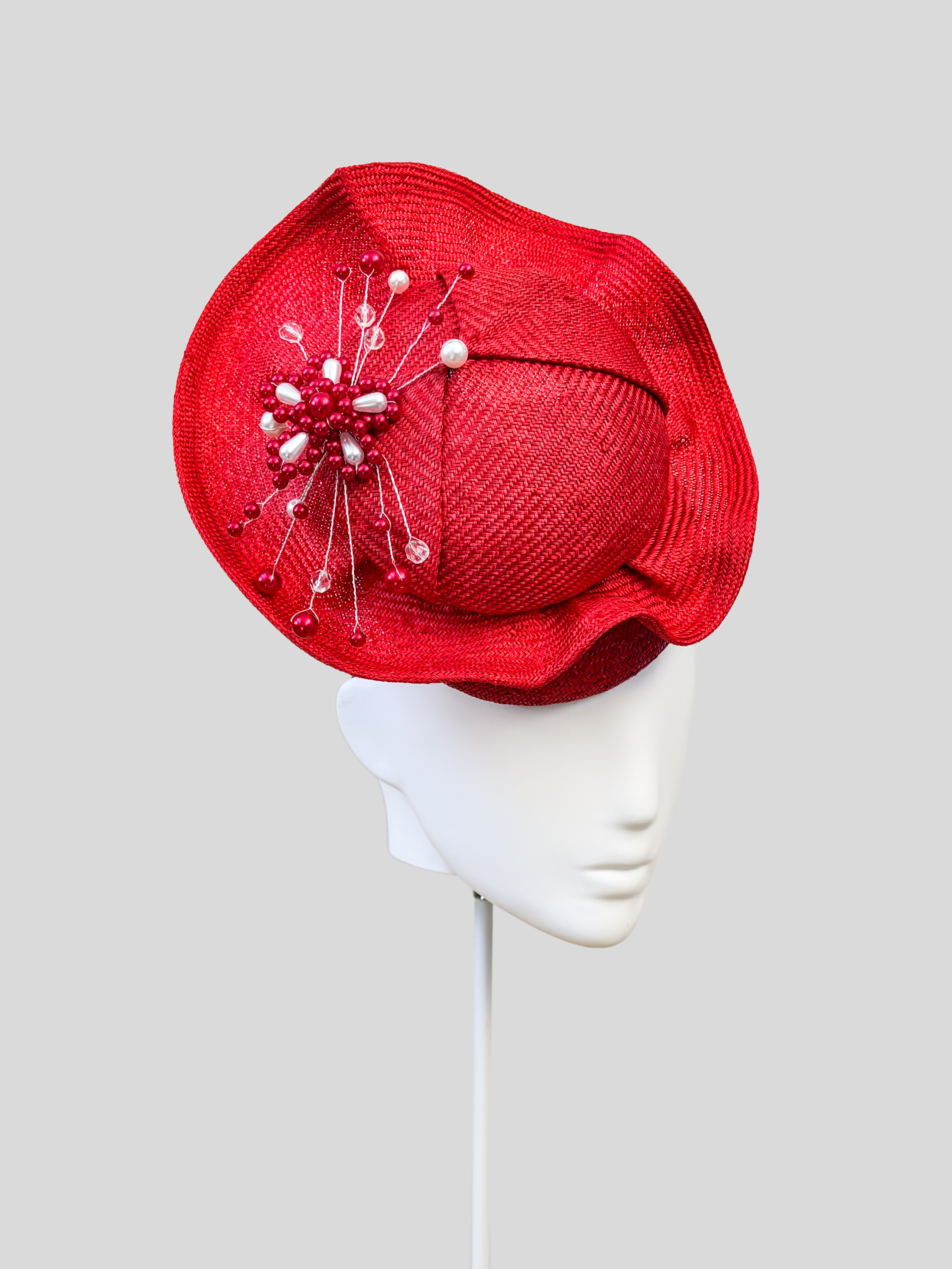 Left: Side view of the VÉRA Ruby Parisisal cocktail hat showcasing its sculptural floating crown and rounded silhouette.
