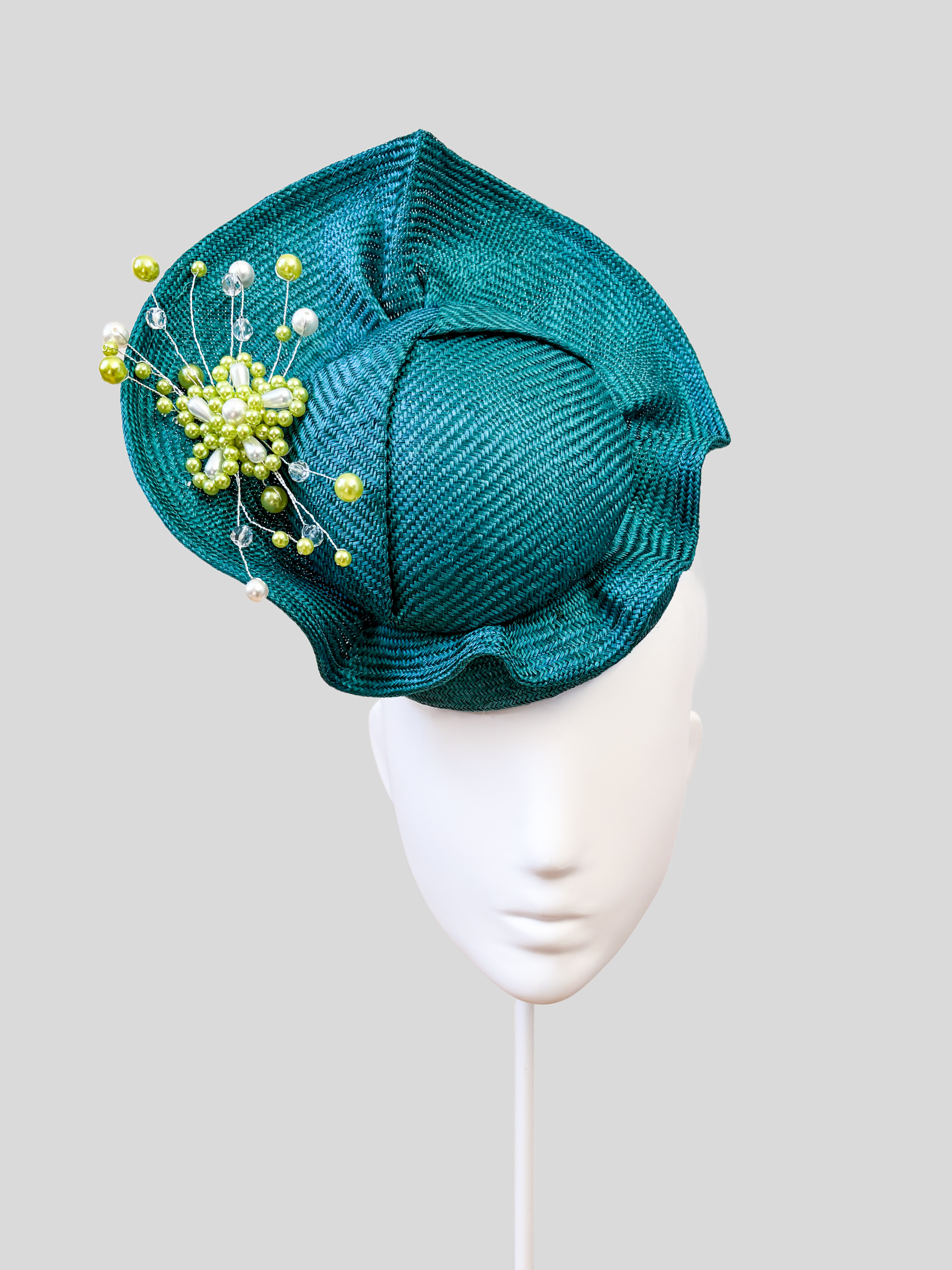 Front: VÉRA Teal Parisisal cocktail hat featuring a sculptural floating crown and hand-beaded teal embellishment.