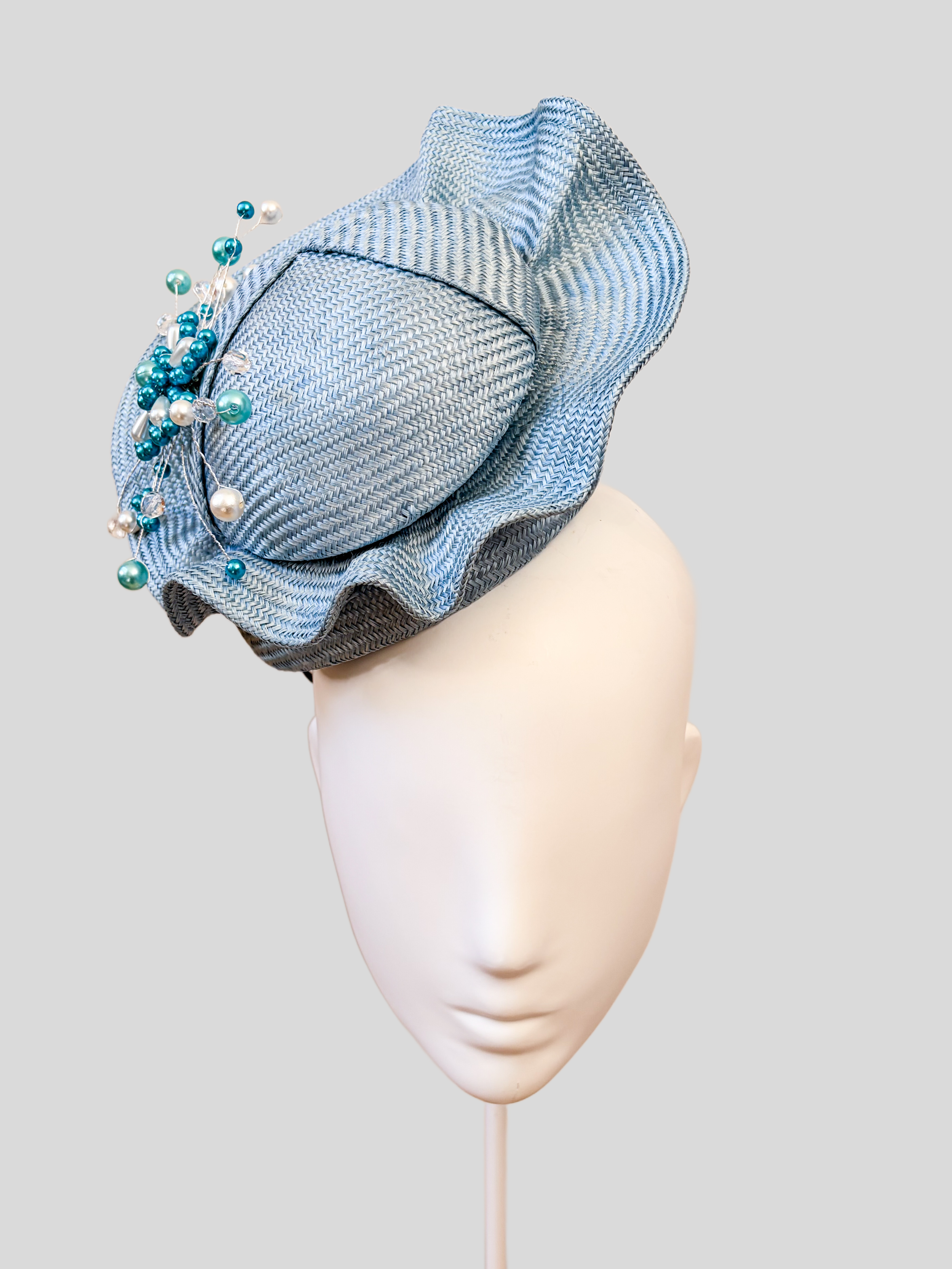 Front: VÉRA Sky Parisisal cocktail hat featuring a sculptural floating crown and hand-beaded blue embellishment.