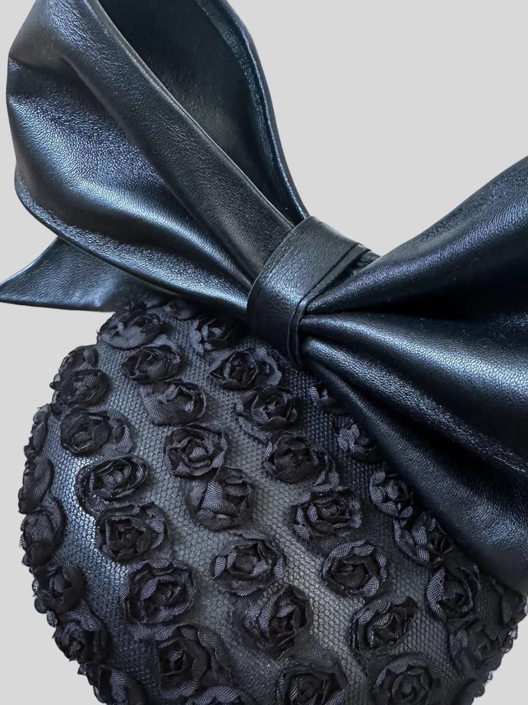 Black rose cocktail hat with leather bow close up view.jpeg