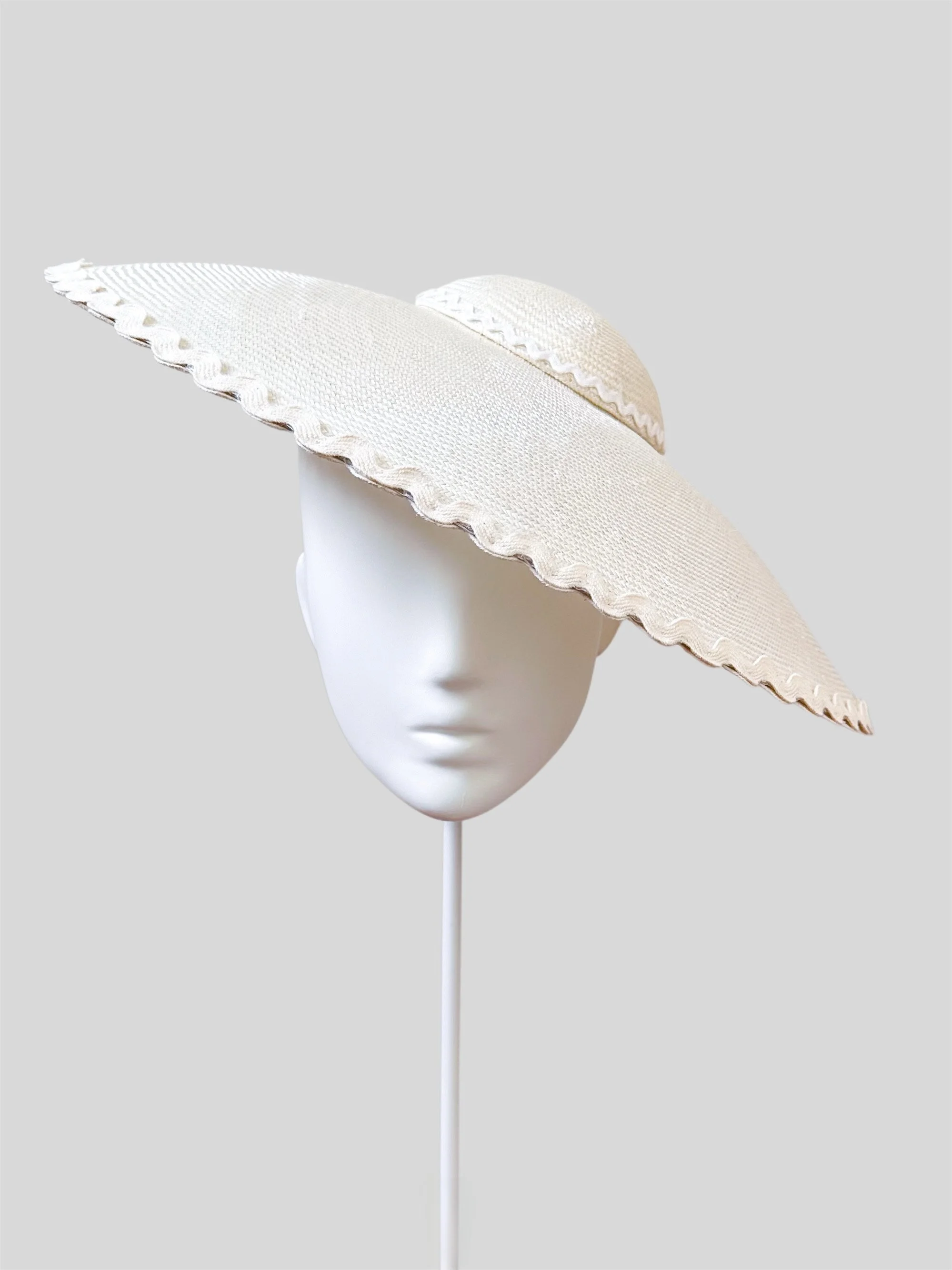 An elegant front-view shot of the Ivory Scalloped Dior Brimmed Hat, showcasing its classic shape, unique scalloped edge, and premium parisisal texture