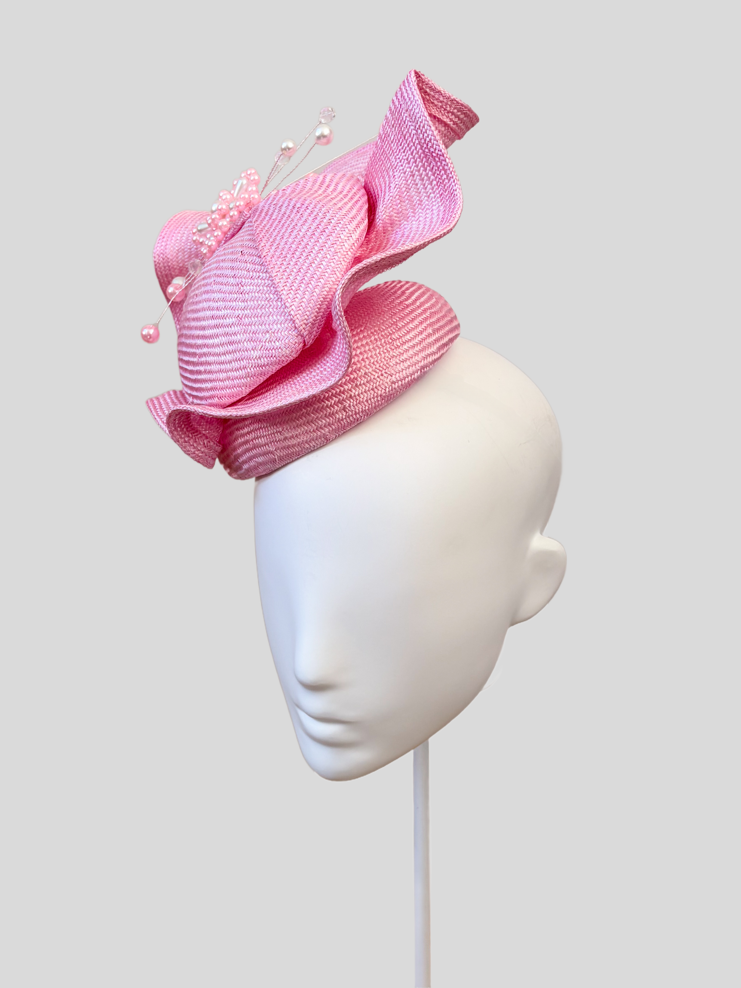 Right: Right-side view of the VÉRA Rose Parisisal cocktail hat highlighting its soft rose-pink finish and hand-beaded embellishment.