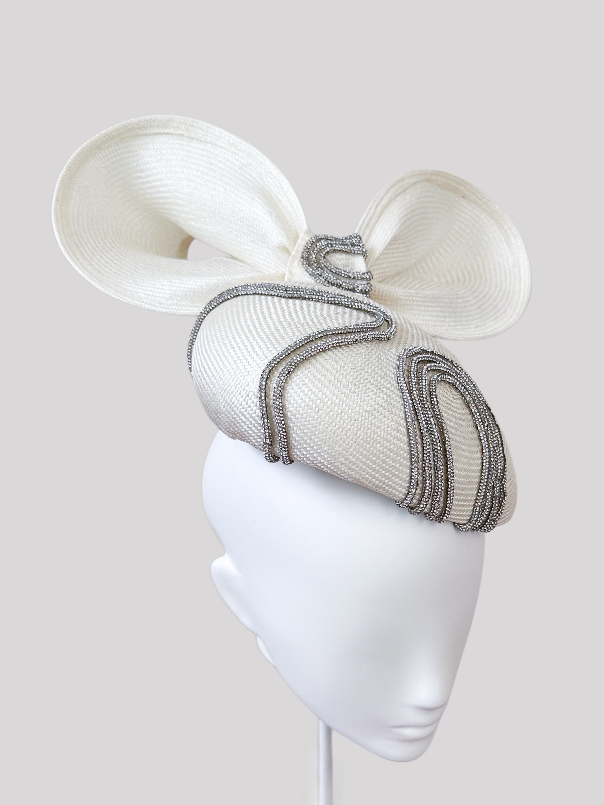 Left profile view of the "Sfavillio Avorio" face hugger. Observe how the metallic silver rope trim accents the off-white parisisal and the shape of the matching bow.