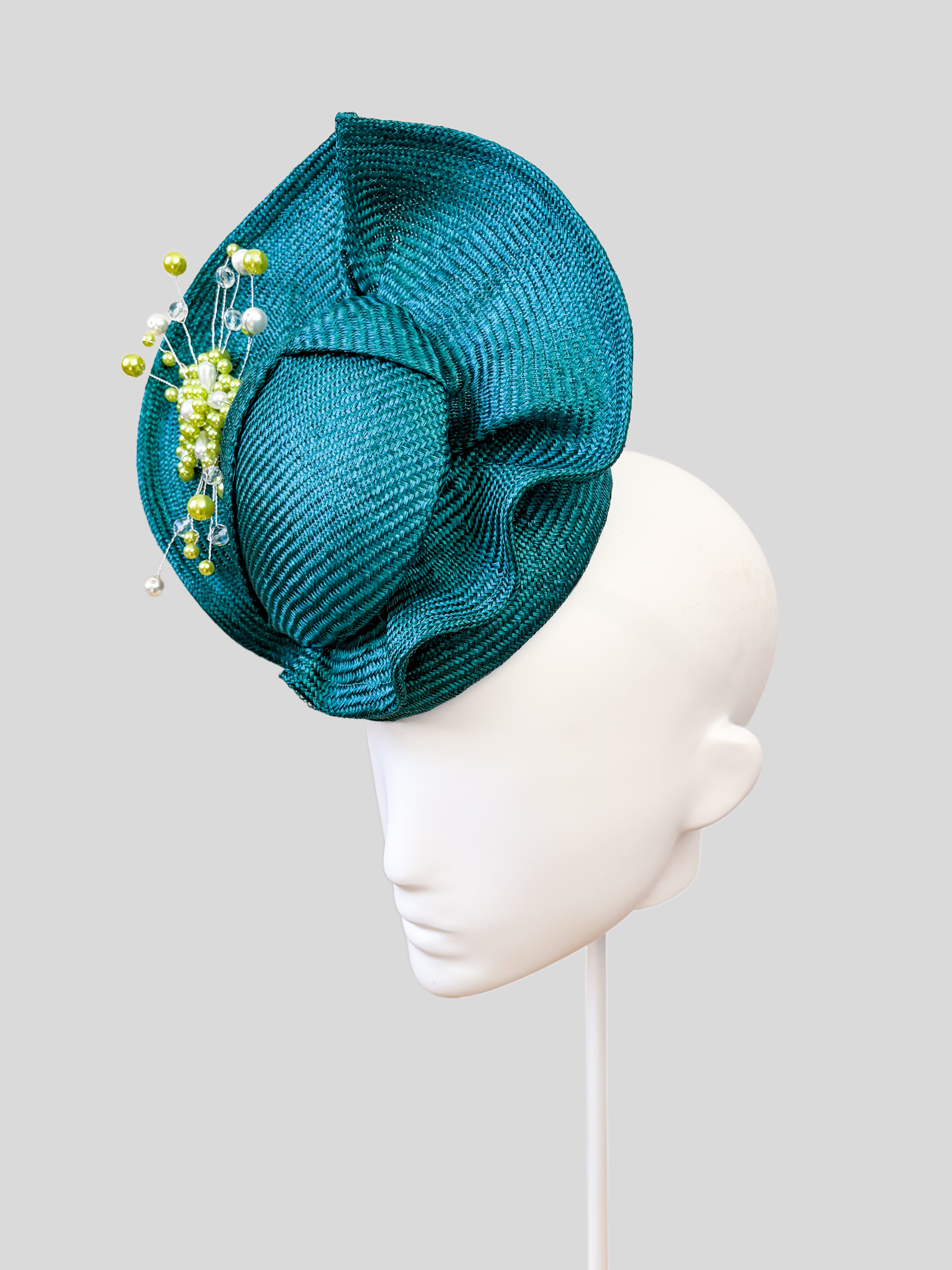 Right: Right-side view of the VÉRA Teal Parisisal cocktail hat highlighting its rich teal-blue finish and hand-beaded embellishment.