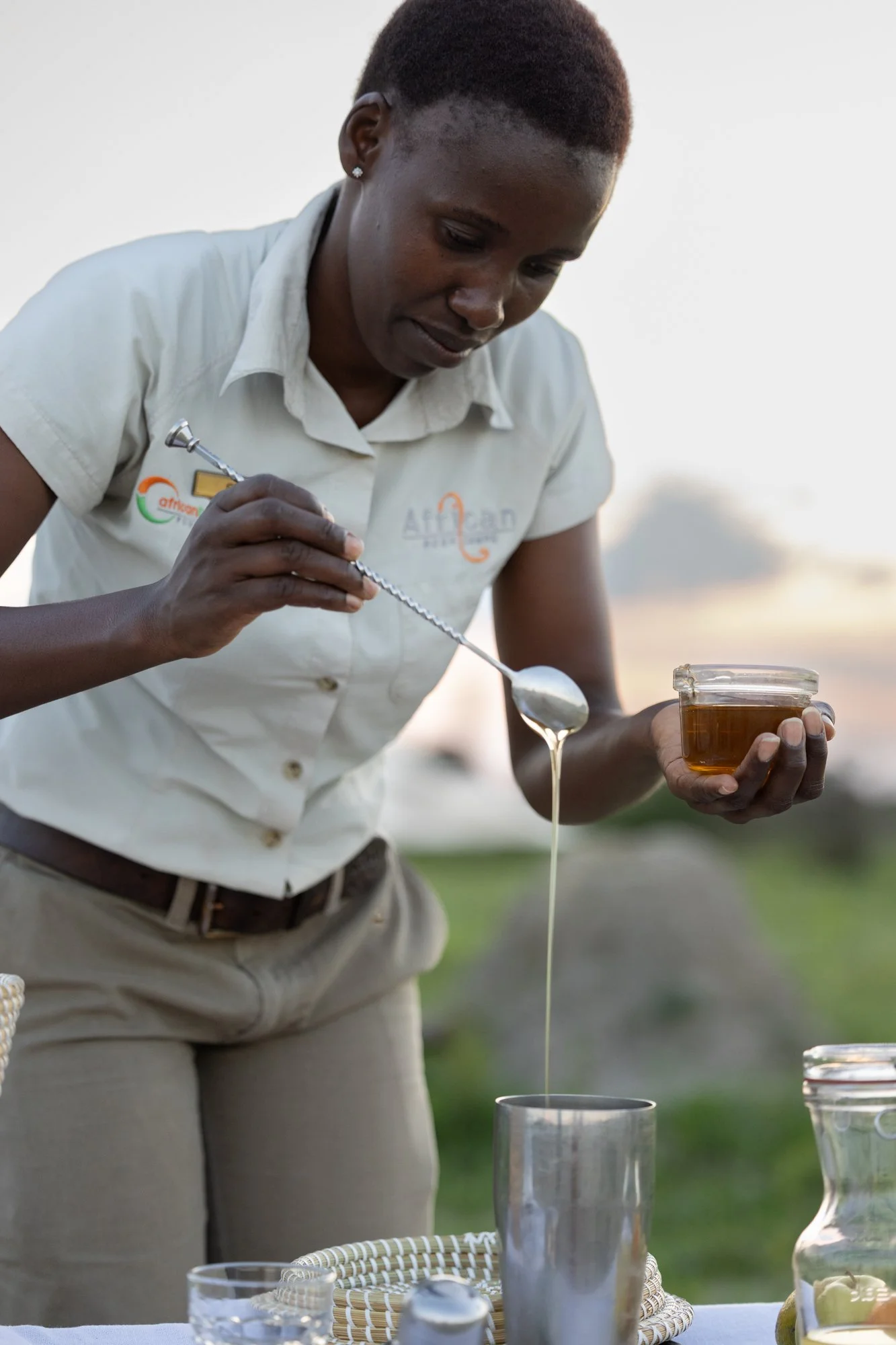 A woman pouring honey into a glass.