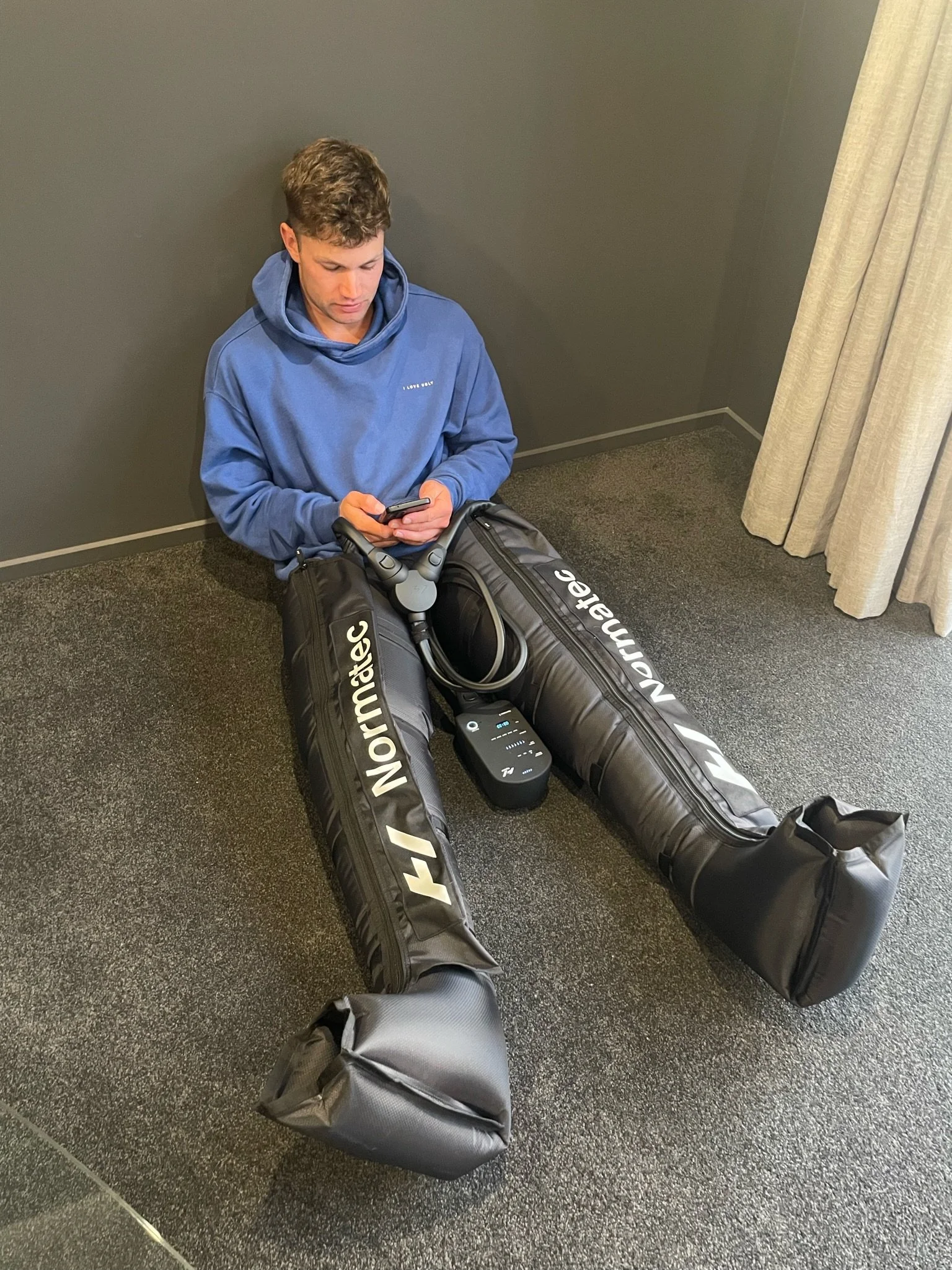 Athlete using Normatec compression boots for post-training leg recovery
