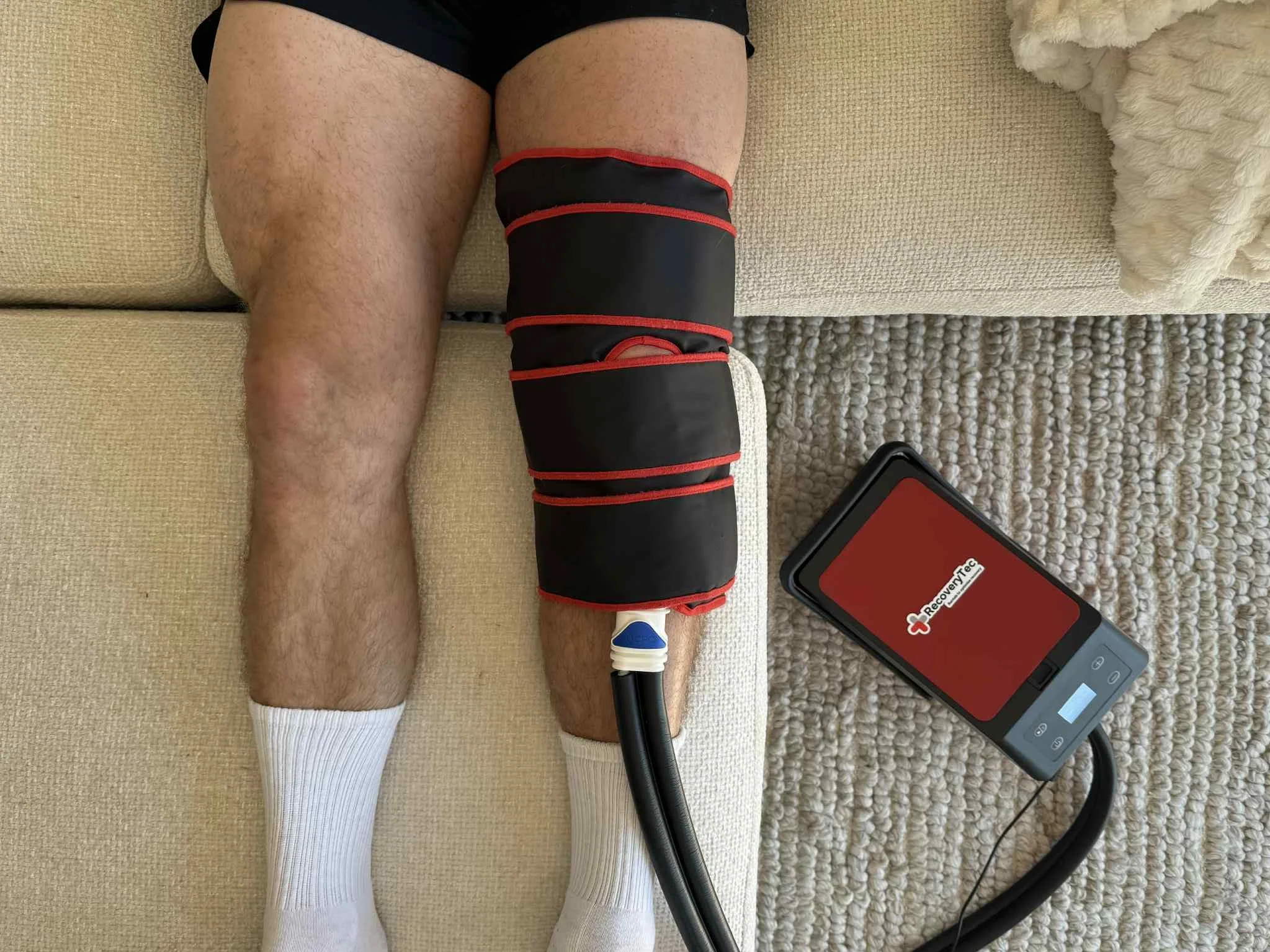 Person lying on the floor with a cold compression cryopush macine device on their leg connected to a portable pump.