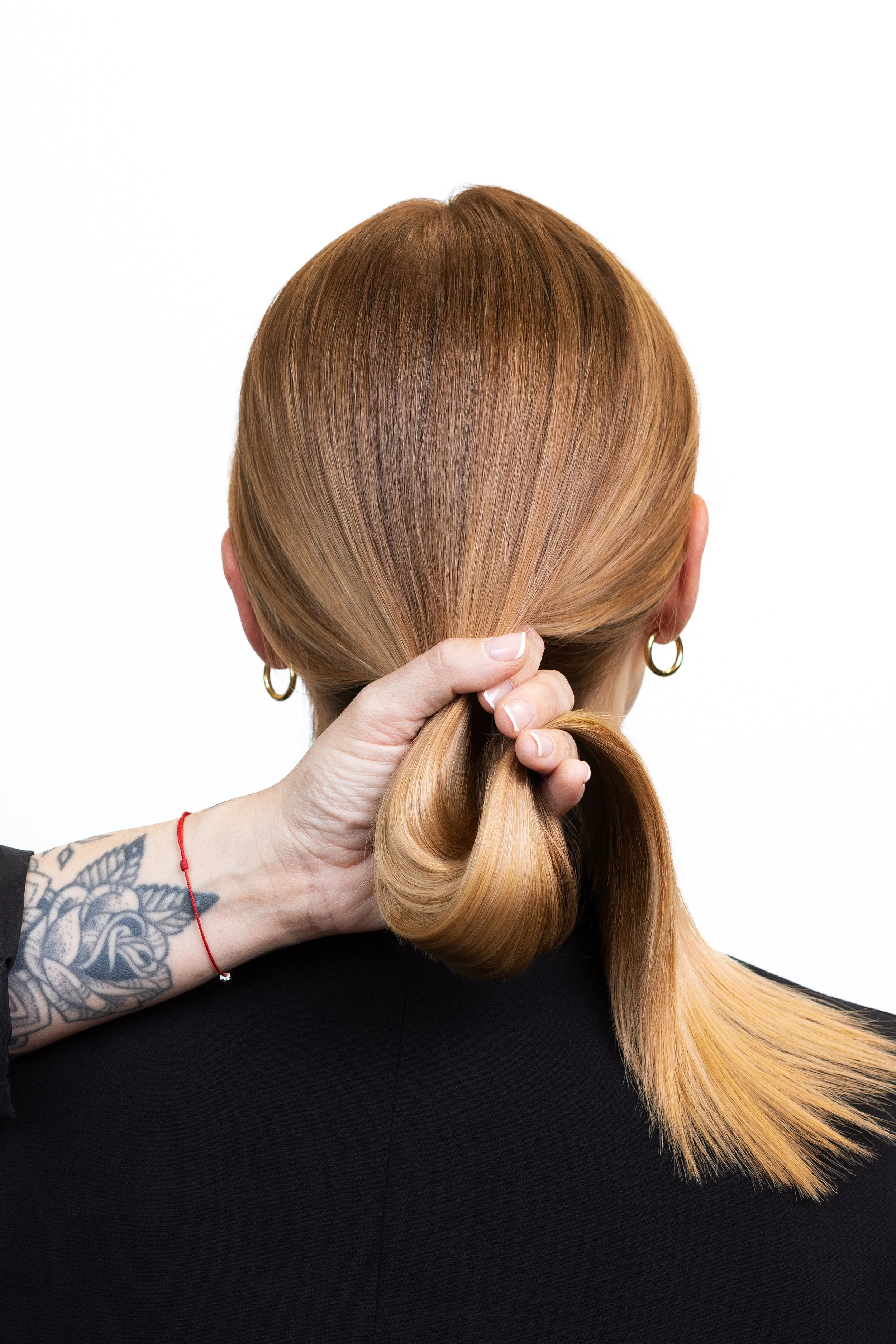 Hair styling image showing a sleek blonde ponytail held by a hairstylist.