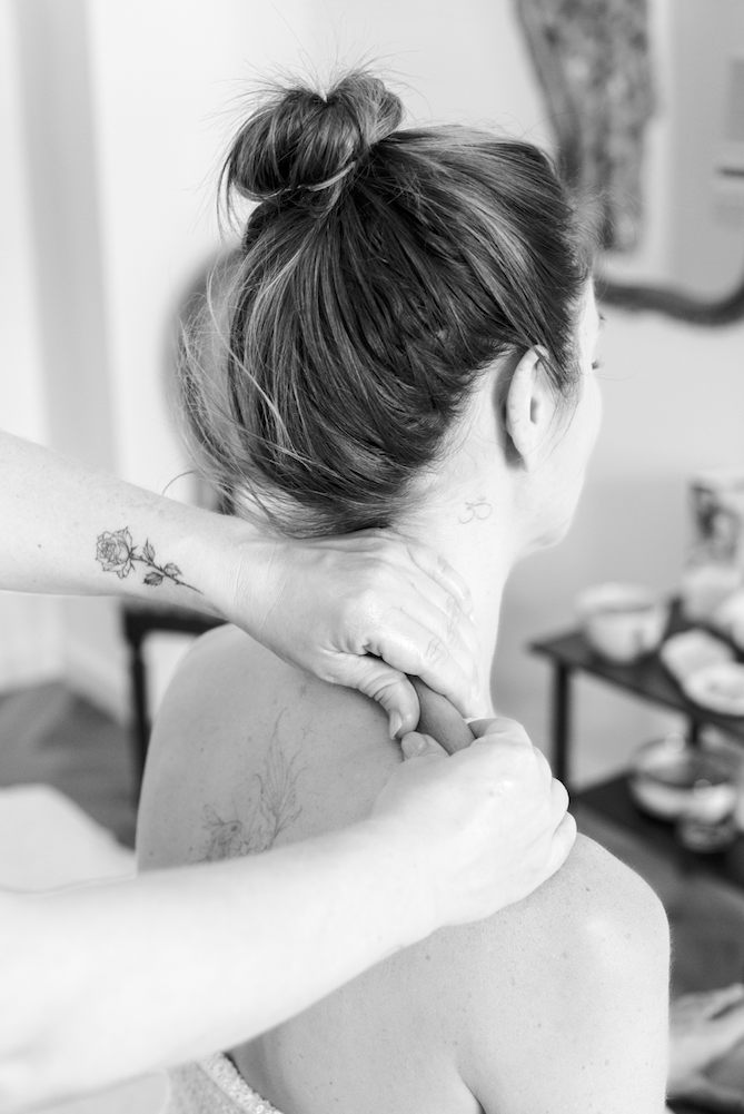 Black and white detail of a practitioner giving a relaxing neck and shoulder massage.