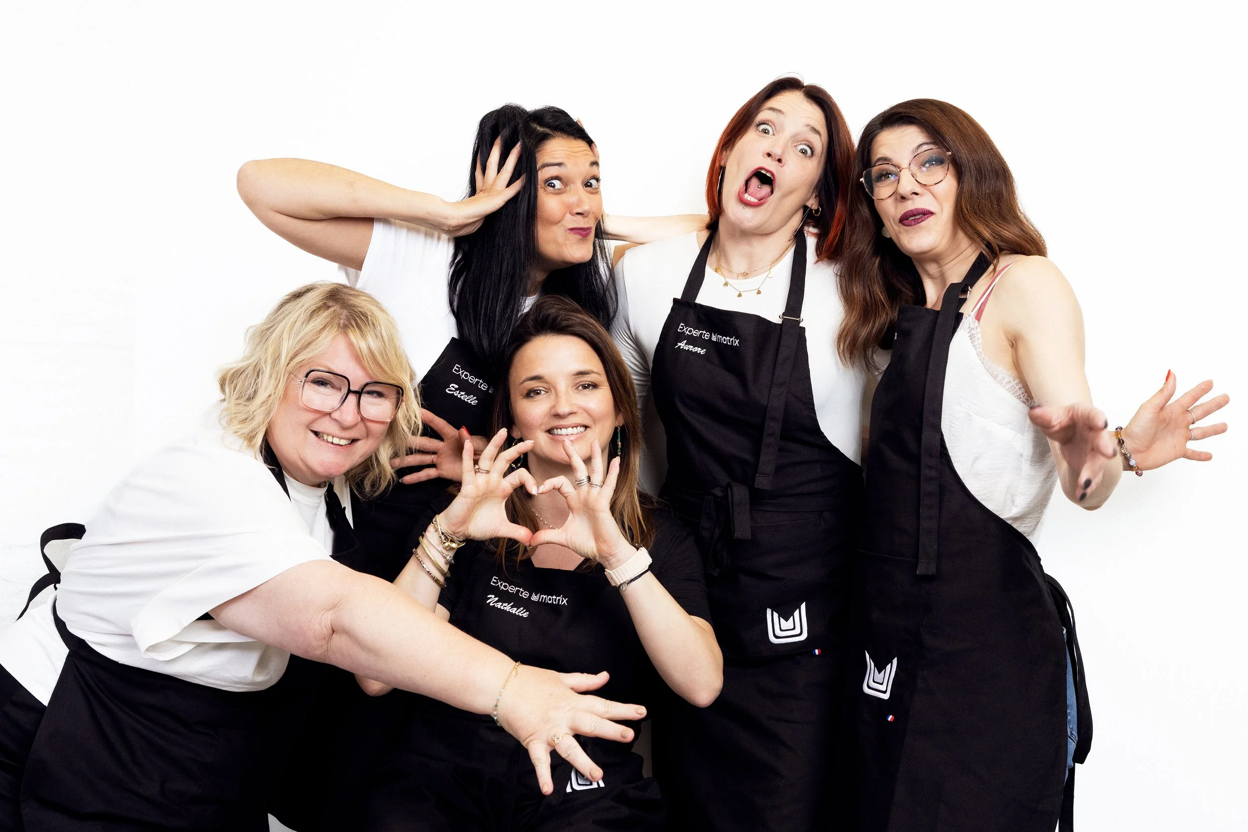 Playful group portrait of five Matrix hair experts photographed together against a white background.