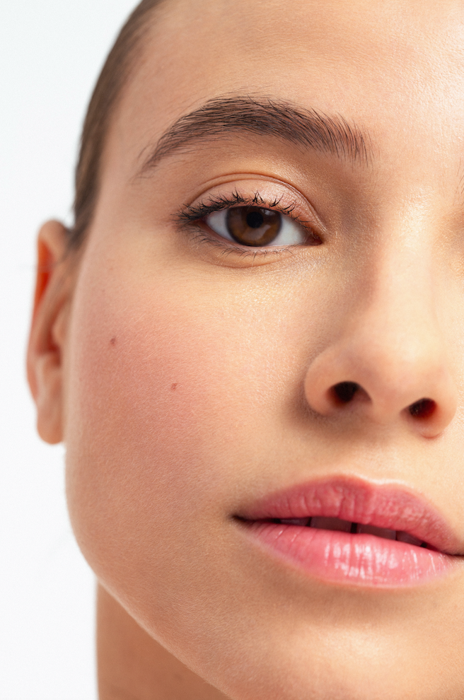 Natural beauty close-up highlighting luminous skin, eye detail and soft pink lips.