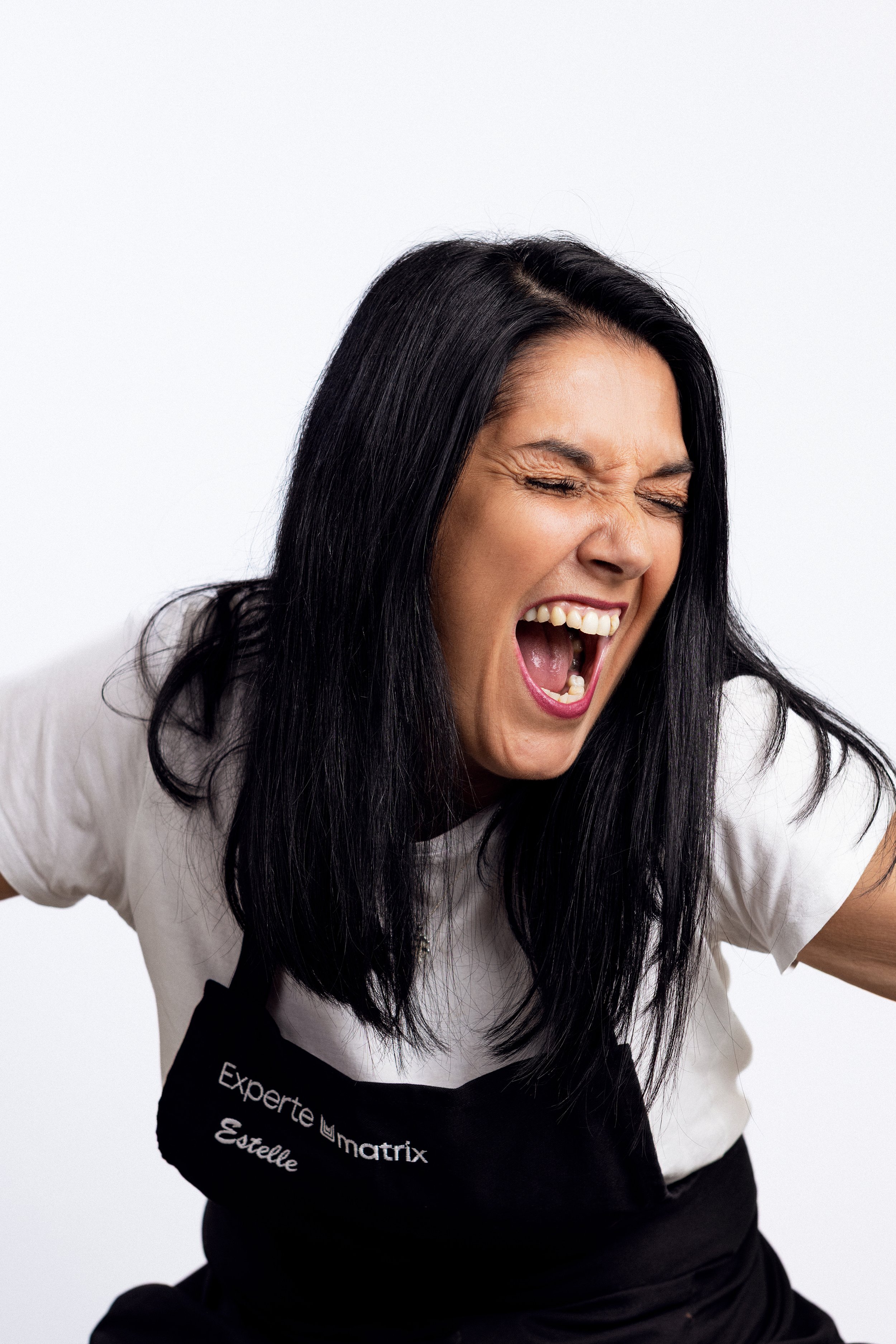 Expressive portrait of a Matrix hair expert laughing during a professional team photoshoot.