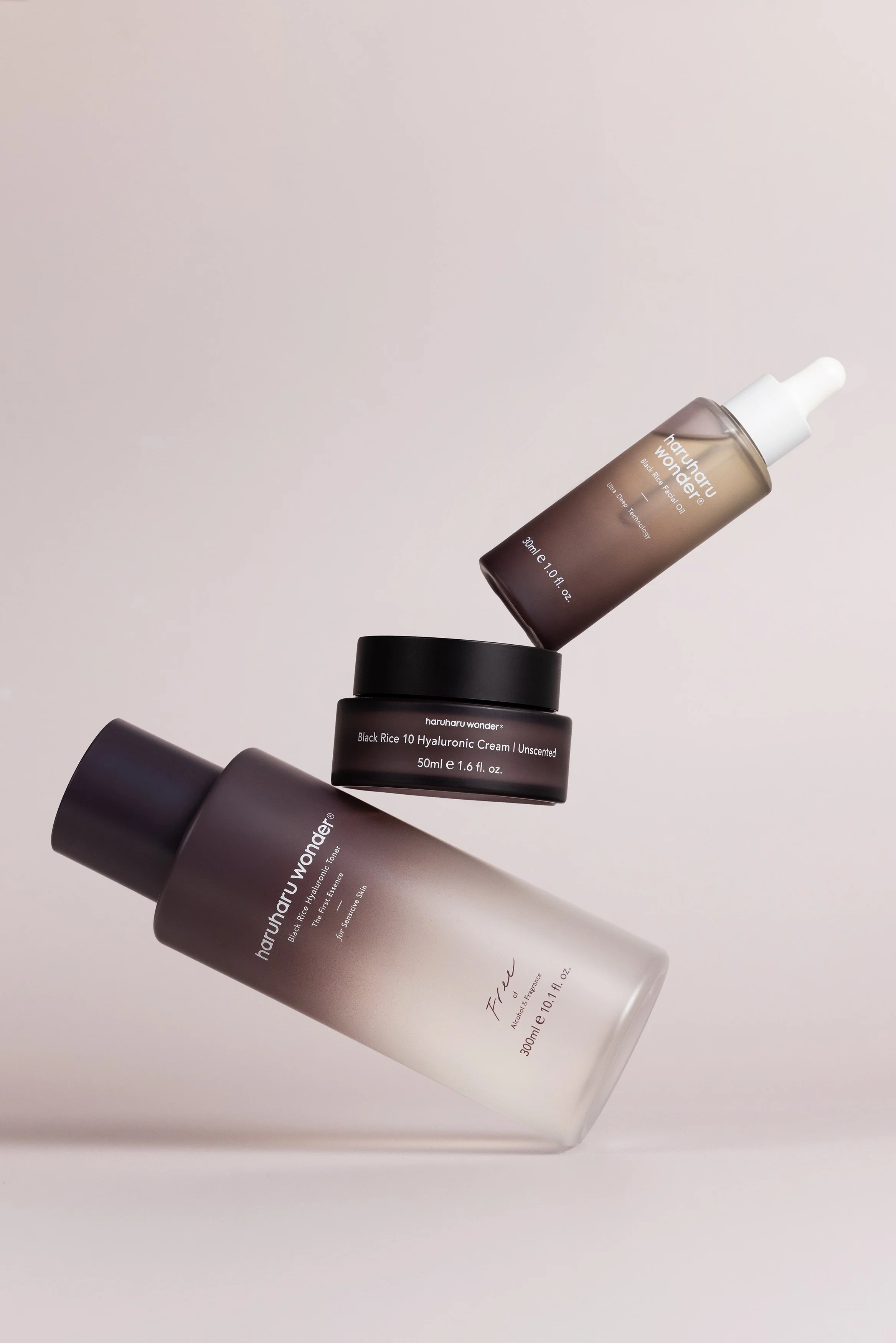 Wonder skincare products balanced in a sculptural composition on a soft neutral background.