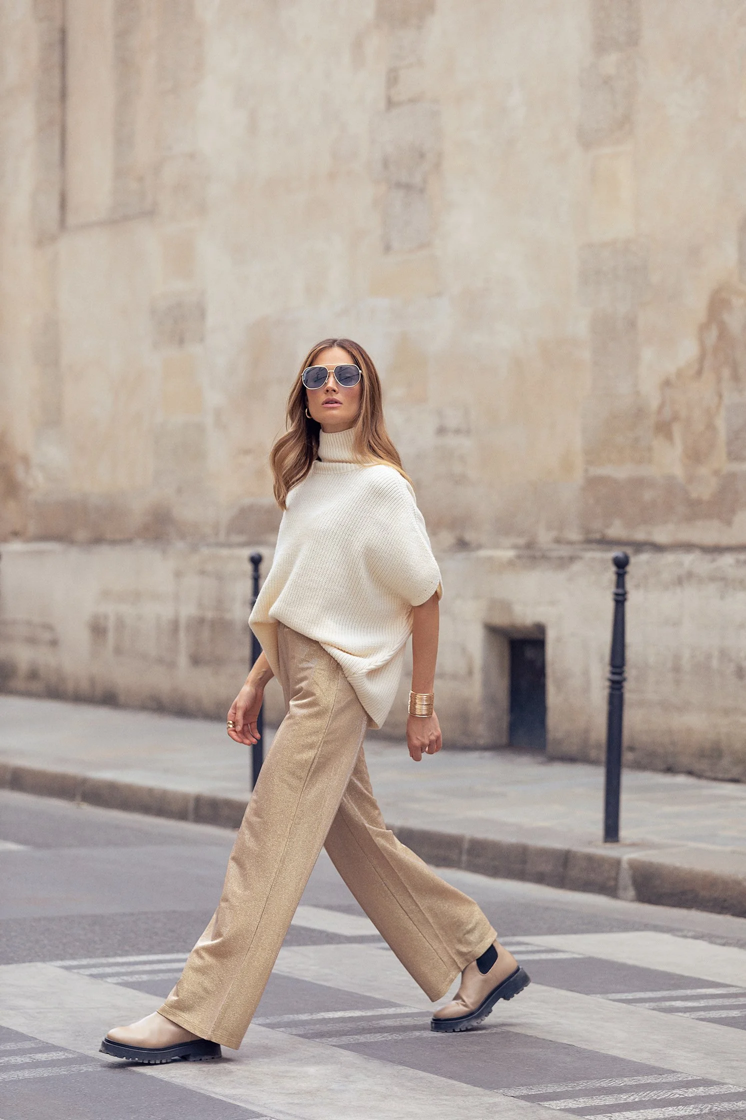 Woman in a neutral beige outfit walking through a Paris street in an editorial fashion photograph.