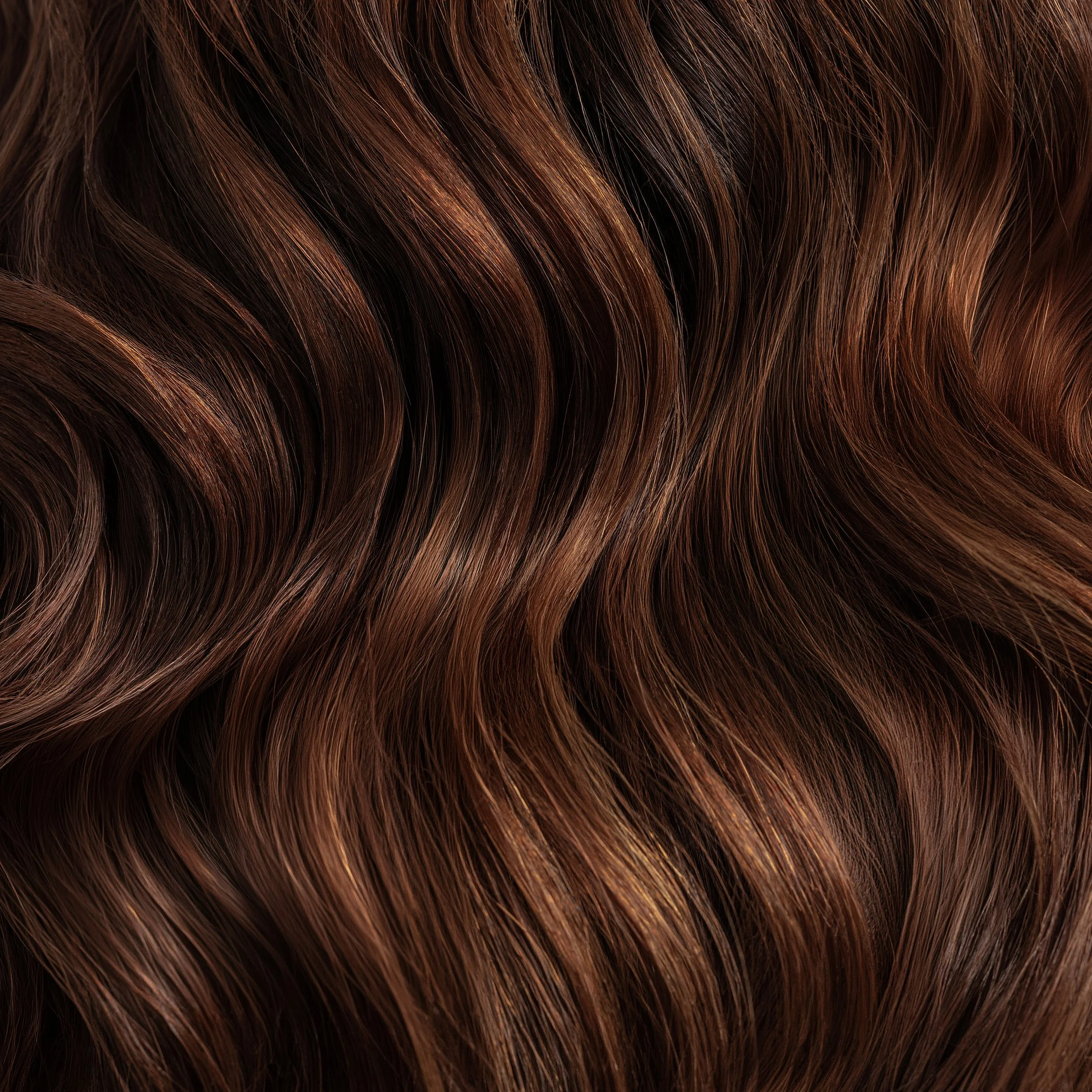 Close-up of glossy brunette waves showing rich brown hair colour and texture.