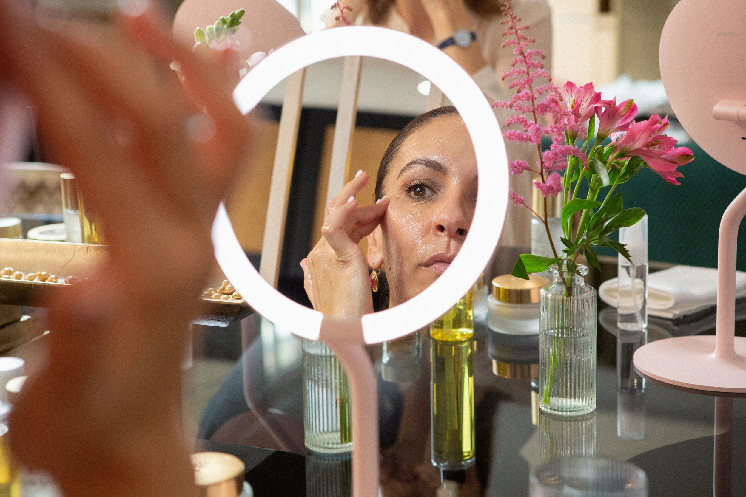 Woman applying skincare while looking into a mirror during a beauty and wellness ritual.