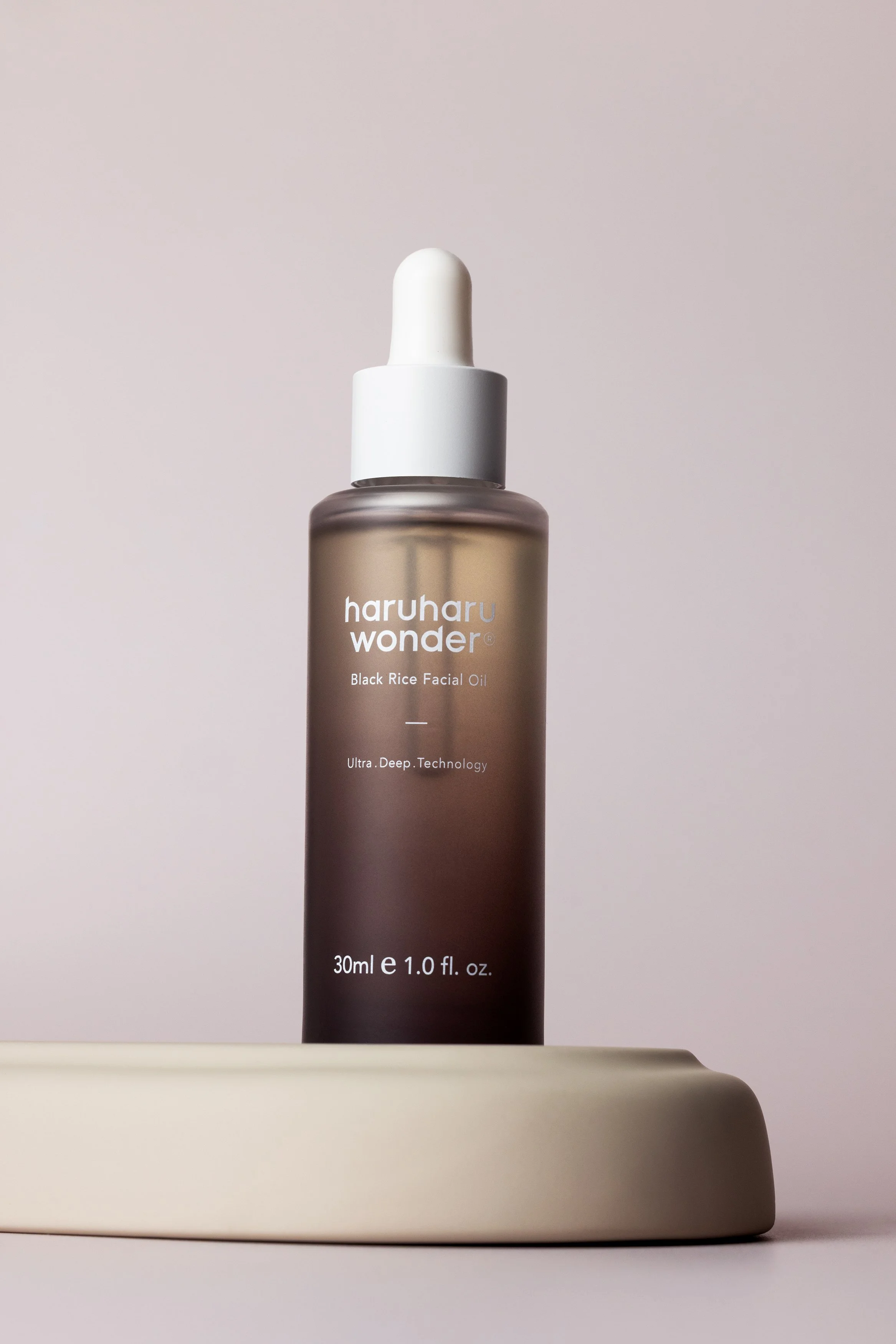 Haruharu Wonder Black Rice Facial Oil photographed on a sculptural neutral set with soft directional light.
