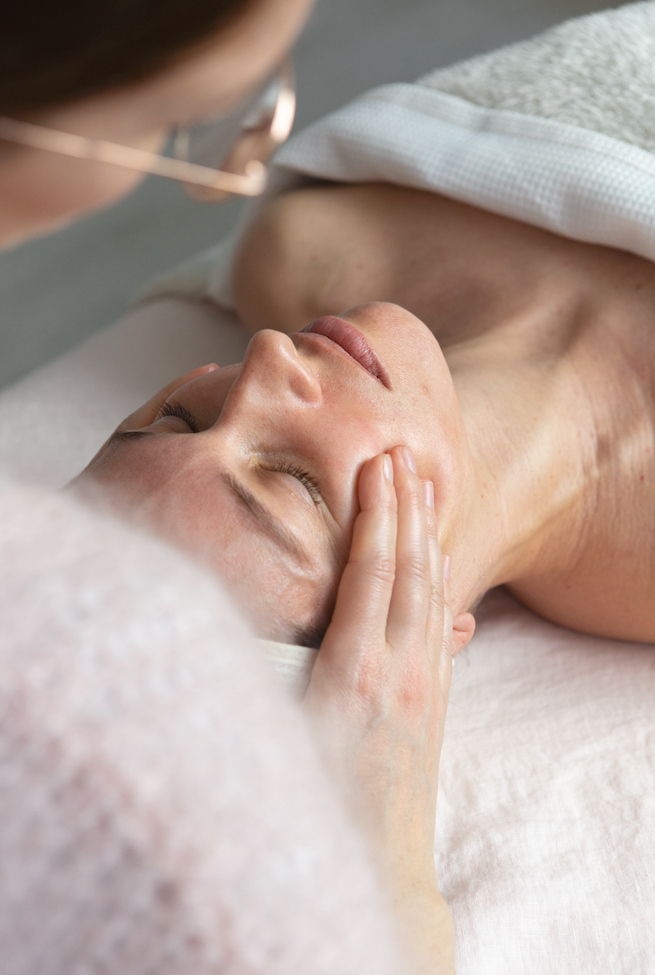 Close-up of a relaxing facial treatment with gentle hands working around the face and temples.